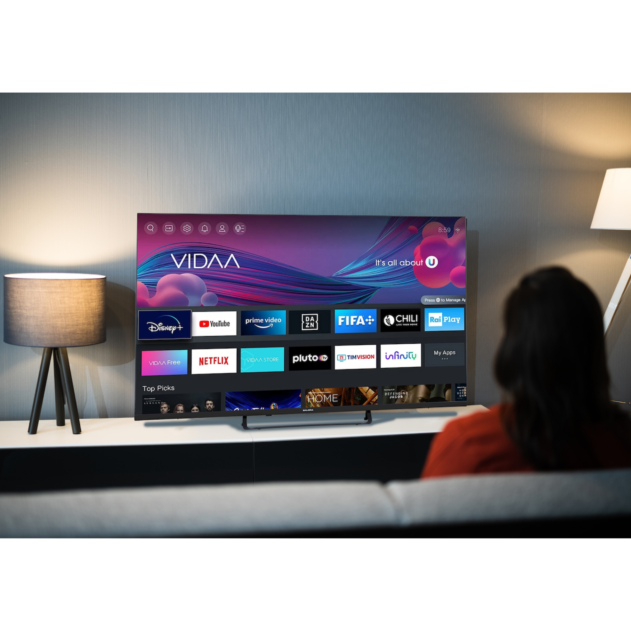 Een persoon die naar een smart-tv kijkt. Verschillende app-iconen worden weergegeven.