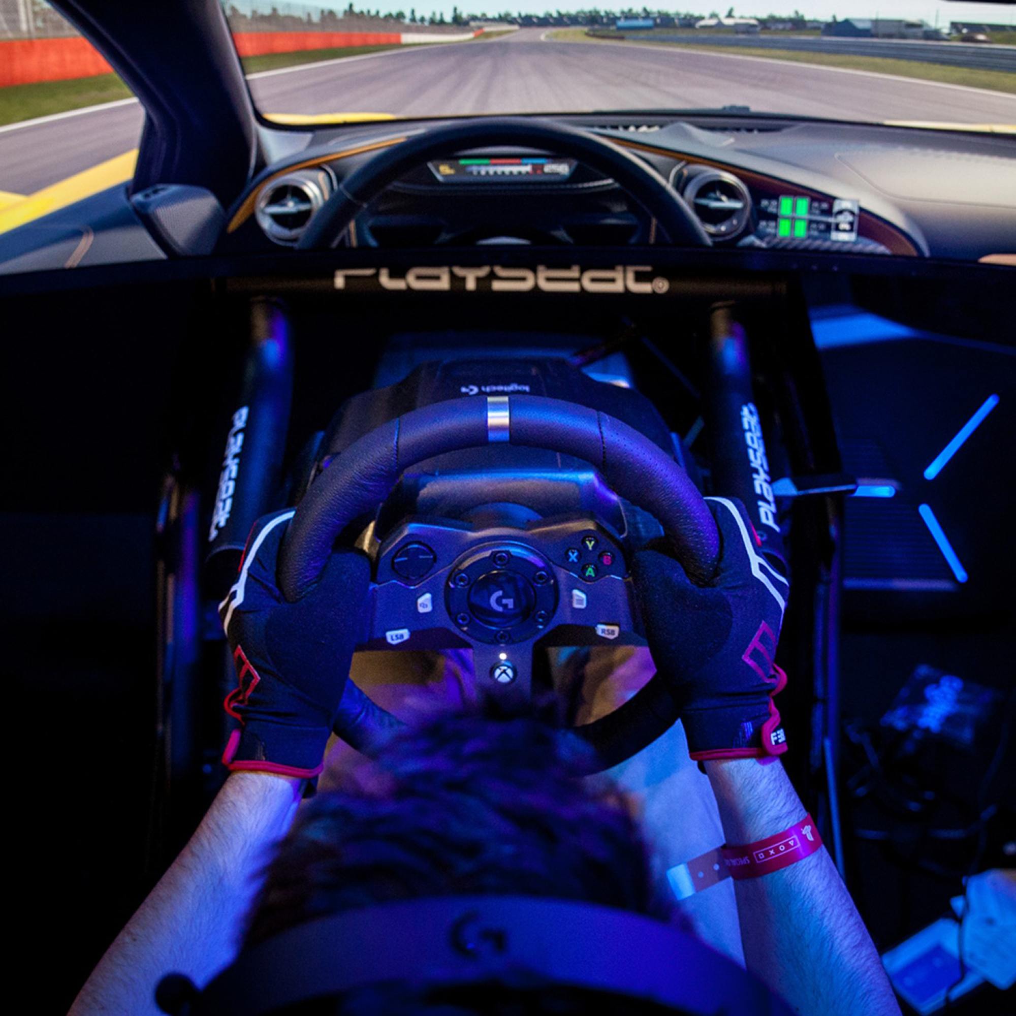 Eine Person mit Handschuhen hält das Lenkrad in einem Rennsimulator, blaue Beleuchtung.