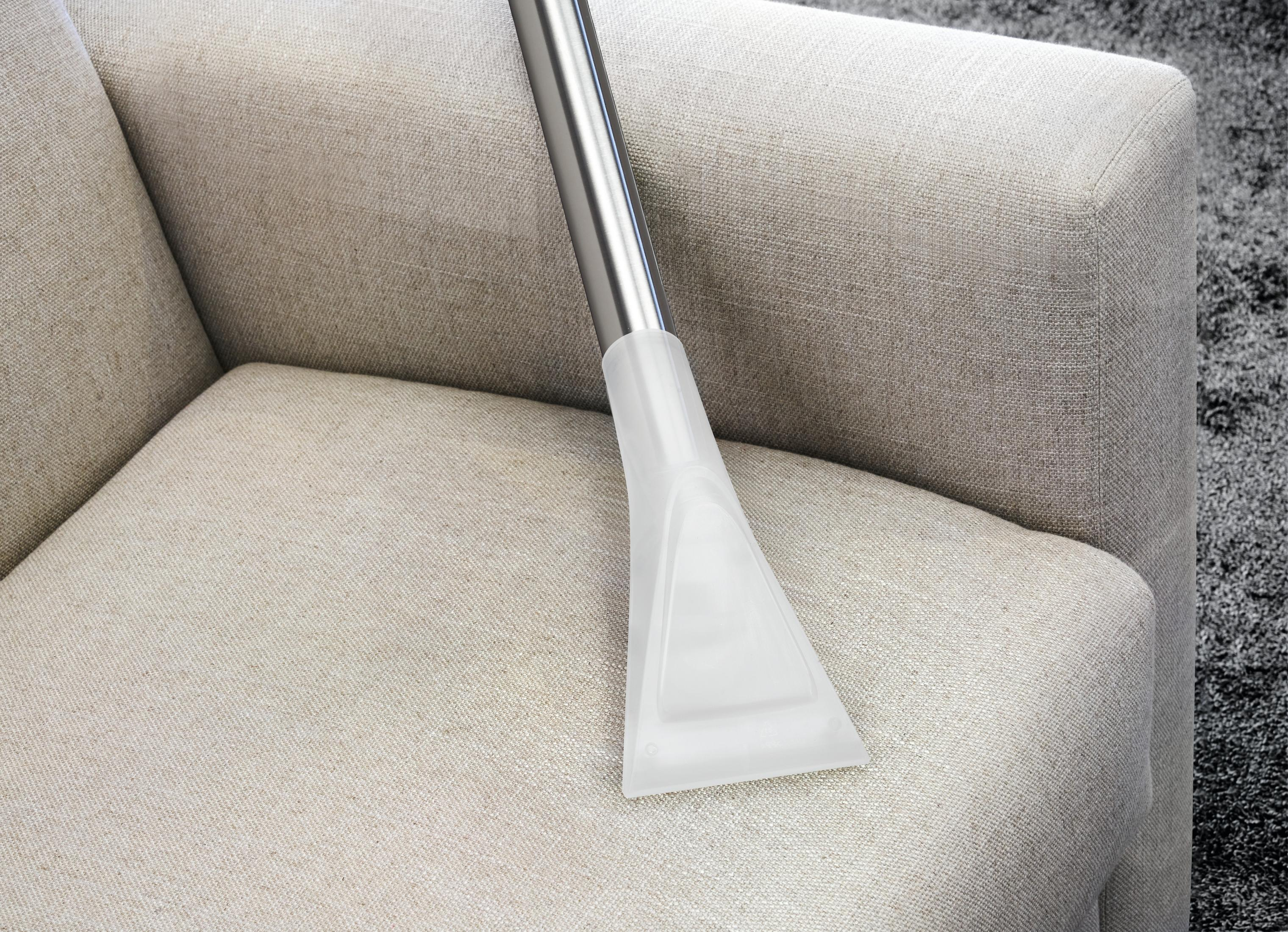 Głowica odkurzacza na beżowej sofie. Sofa jest jasnego koloru.