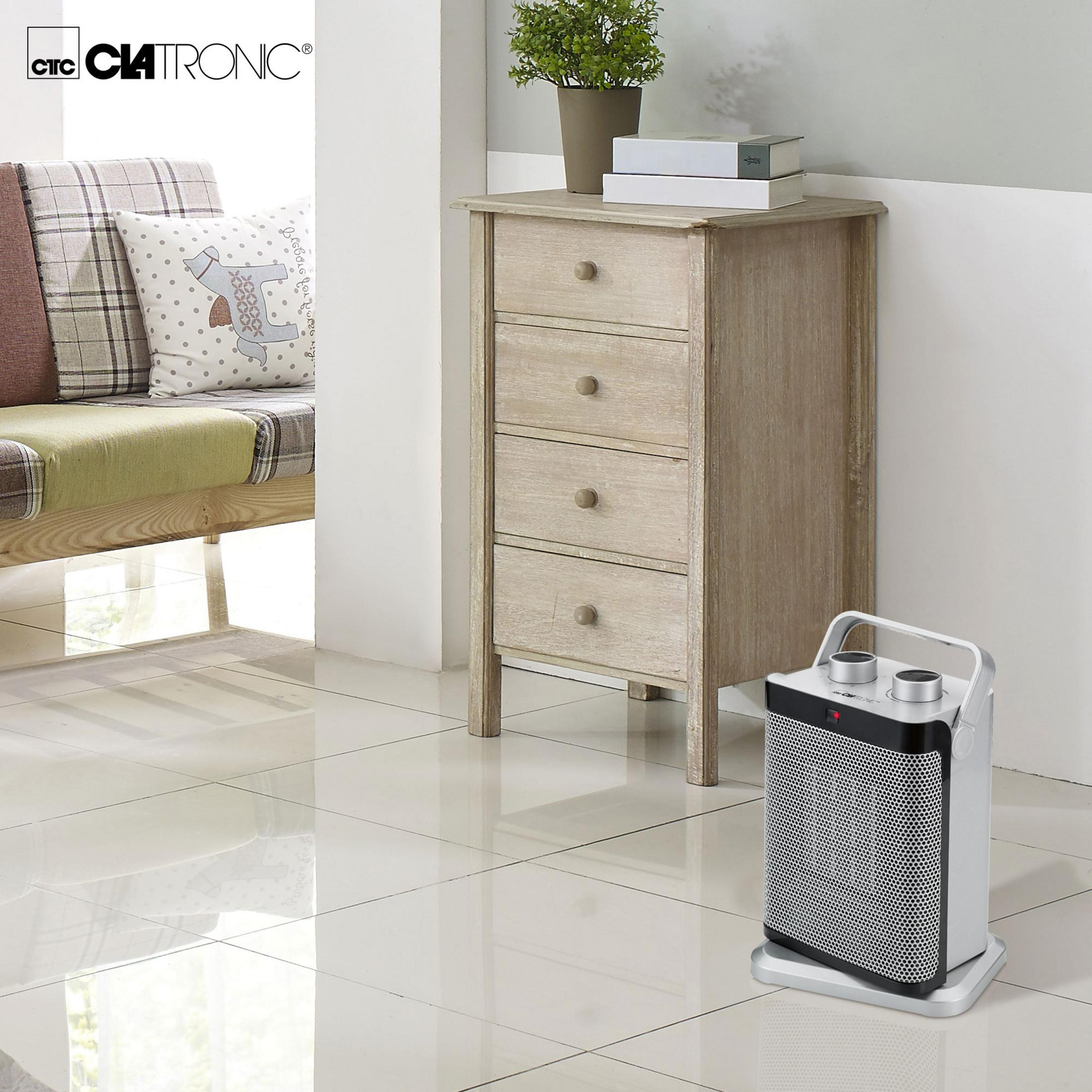 Wnętrze pokoju z drewnianą szafką, grzejnikiem Clatronic i sofą z poduszkami na kafelkowej podłodze.