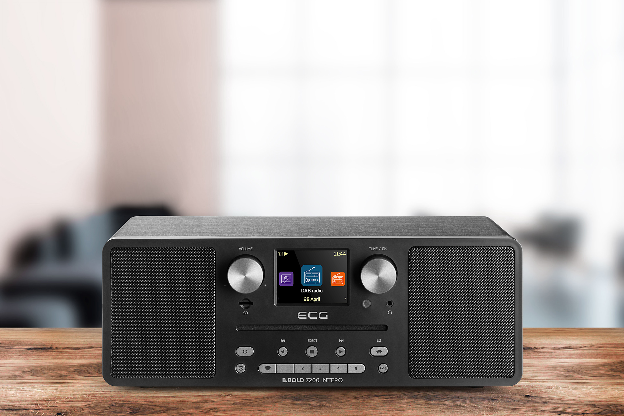 Una radio DAB nera con display è posizionata su un tavolo di legno.