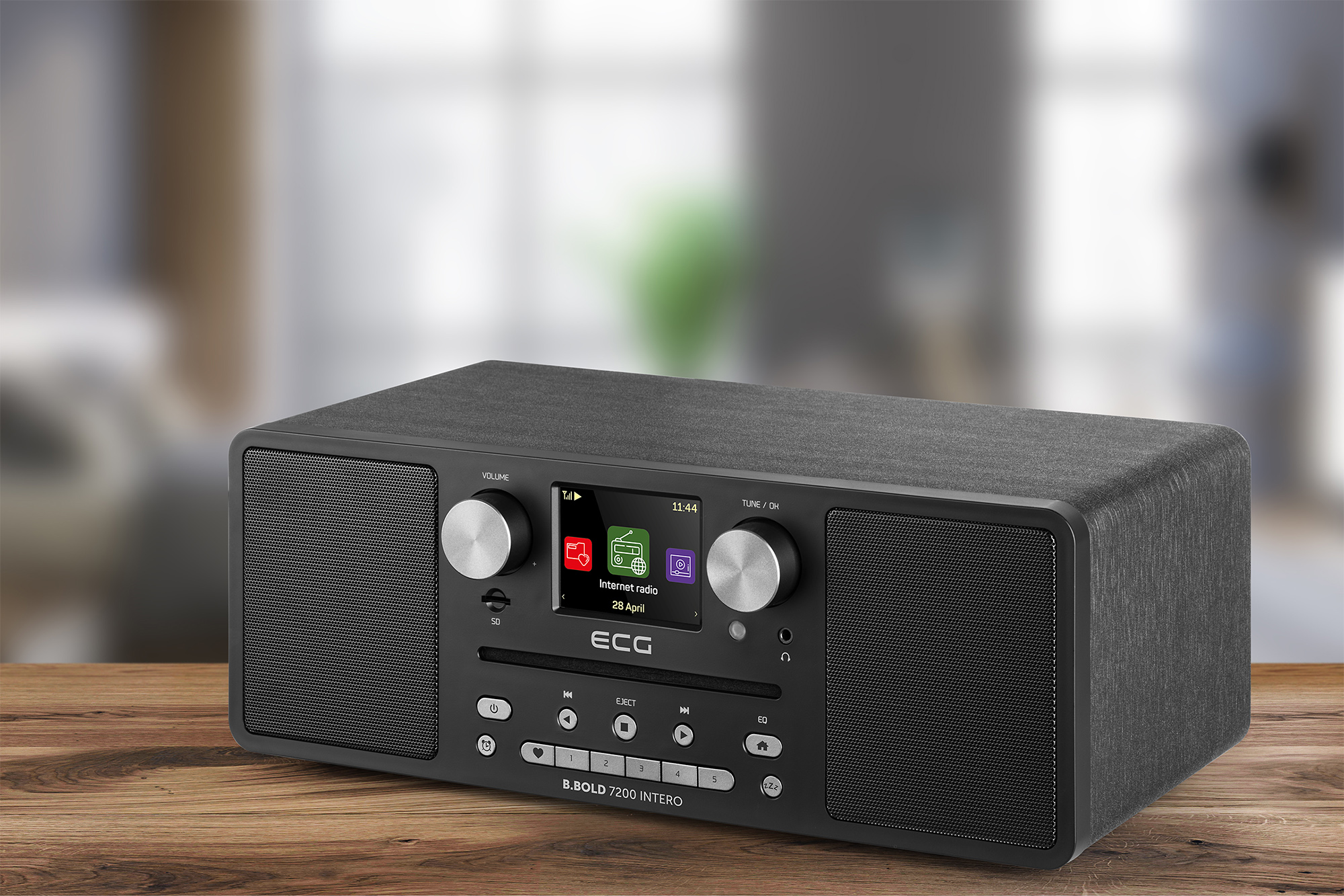 Radio in legno nero con schermo e manopole su un tavolo di legno con sfondo sfocato.