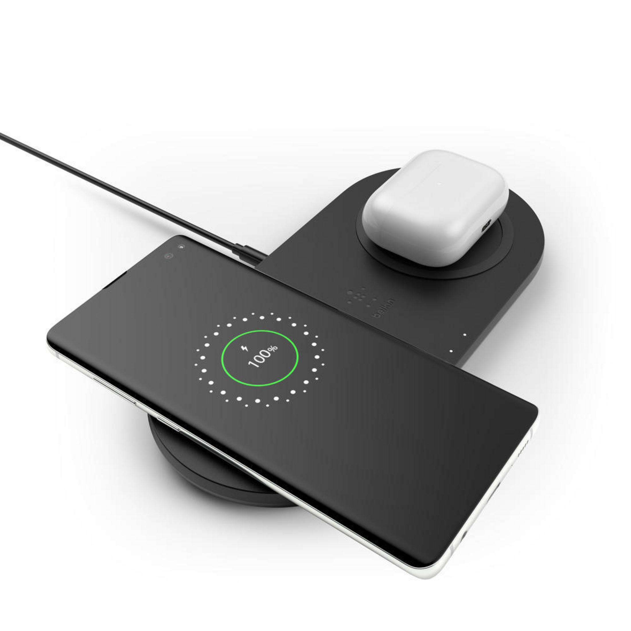 Schwarzes kabelloses Ladegerät mit Telefon und Kopfhörern. Telefon zeigt 100%.