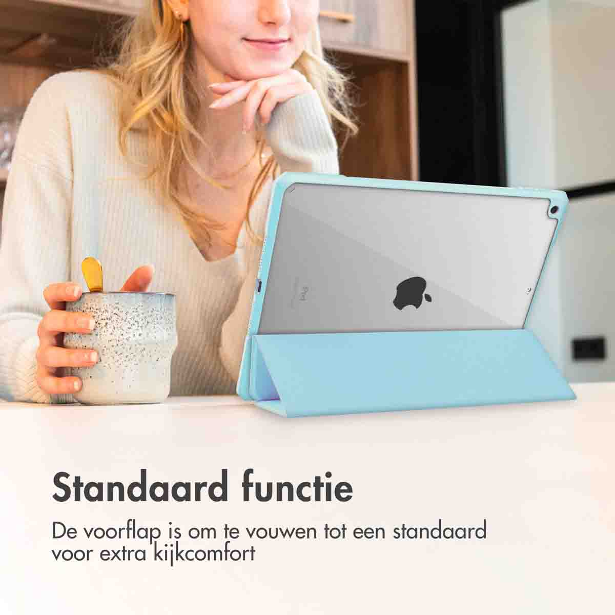 A woman holding a coffee cup and a tablet with a blue case. The tablet is propped up.