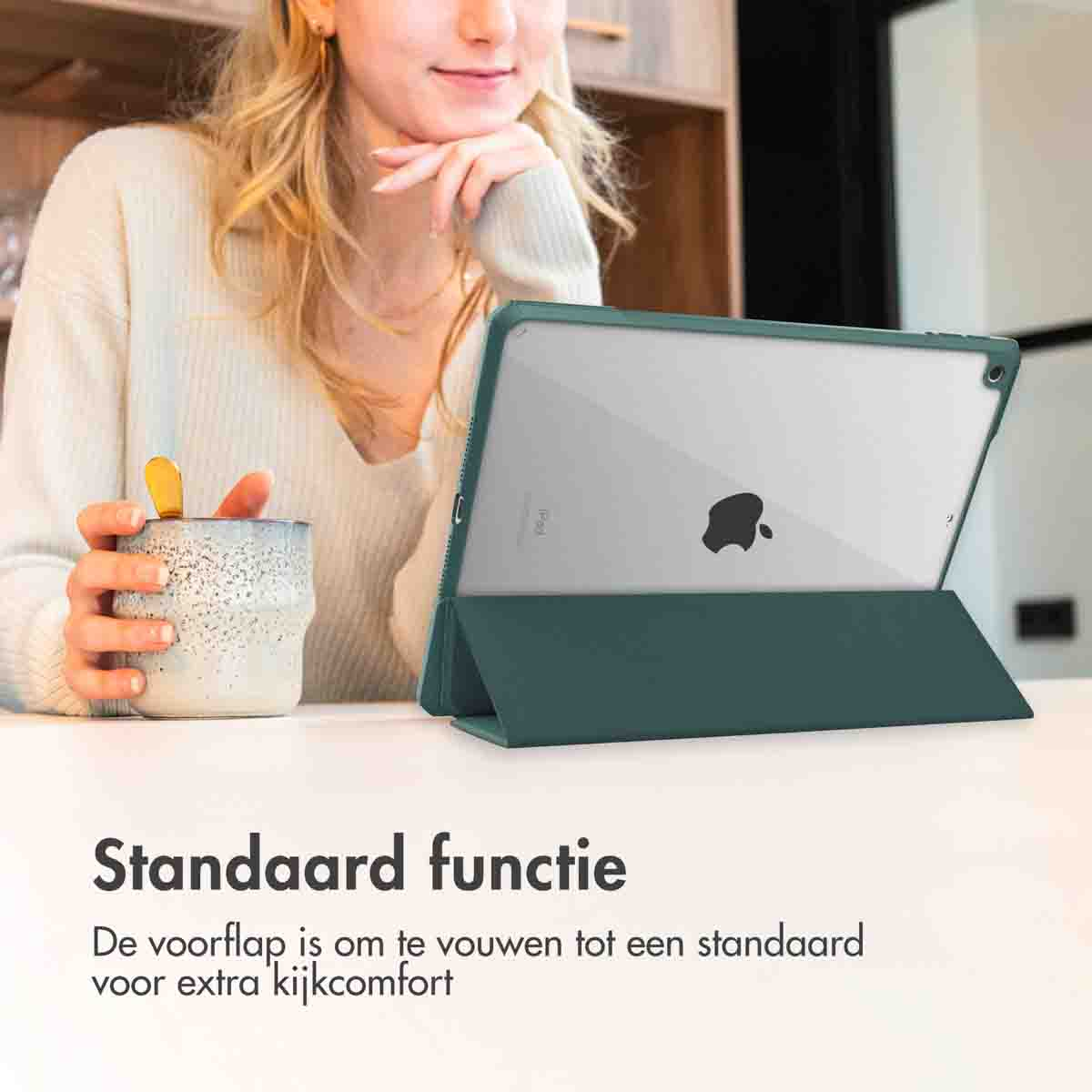Een vrouw met een tablet in een groene hoes, zittend aan een tafel. De hoes is opgevouwen.