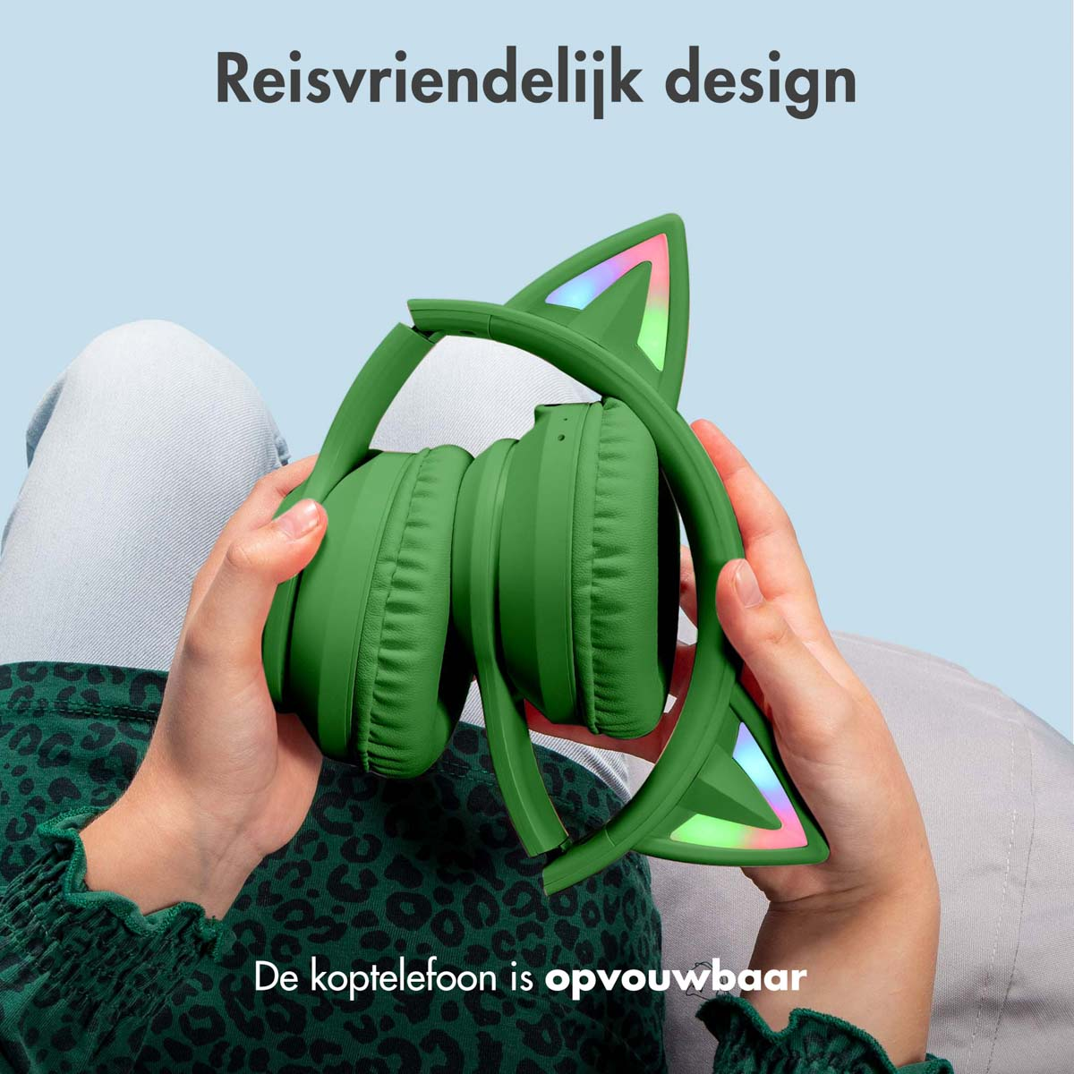 Een persoon die een groene koptelefoon met kattenoren vasthoudt. De koptelefoon is opvouwbaar en kleurrijk.