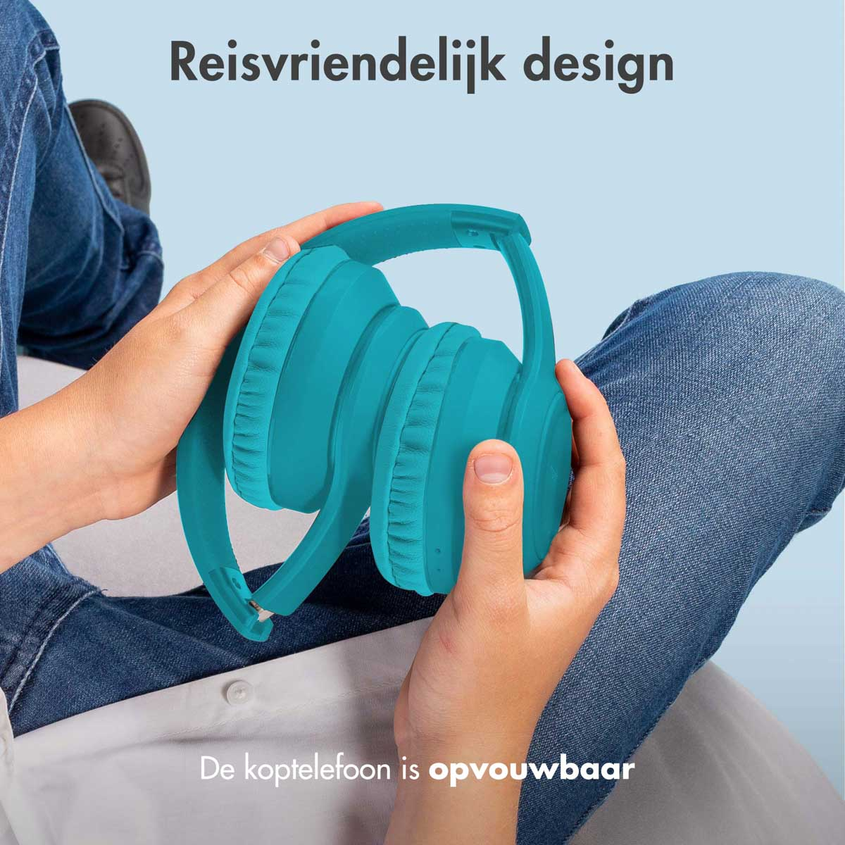 Handen houden een blauwe opgevouwen koptelefoon vast. Blauwe achtergrond. Jeans op de achtergrond.