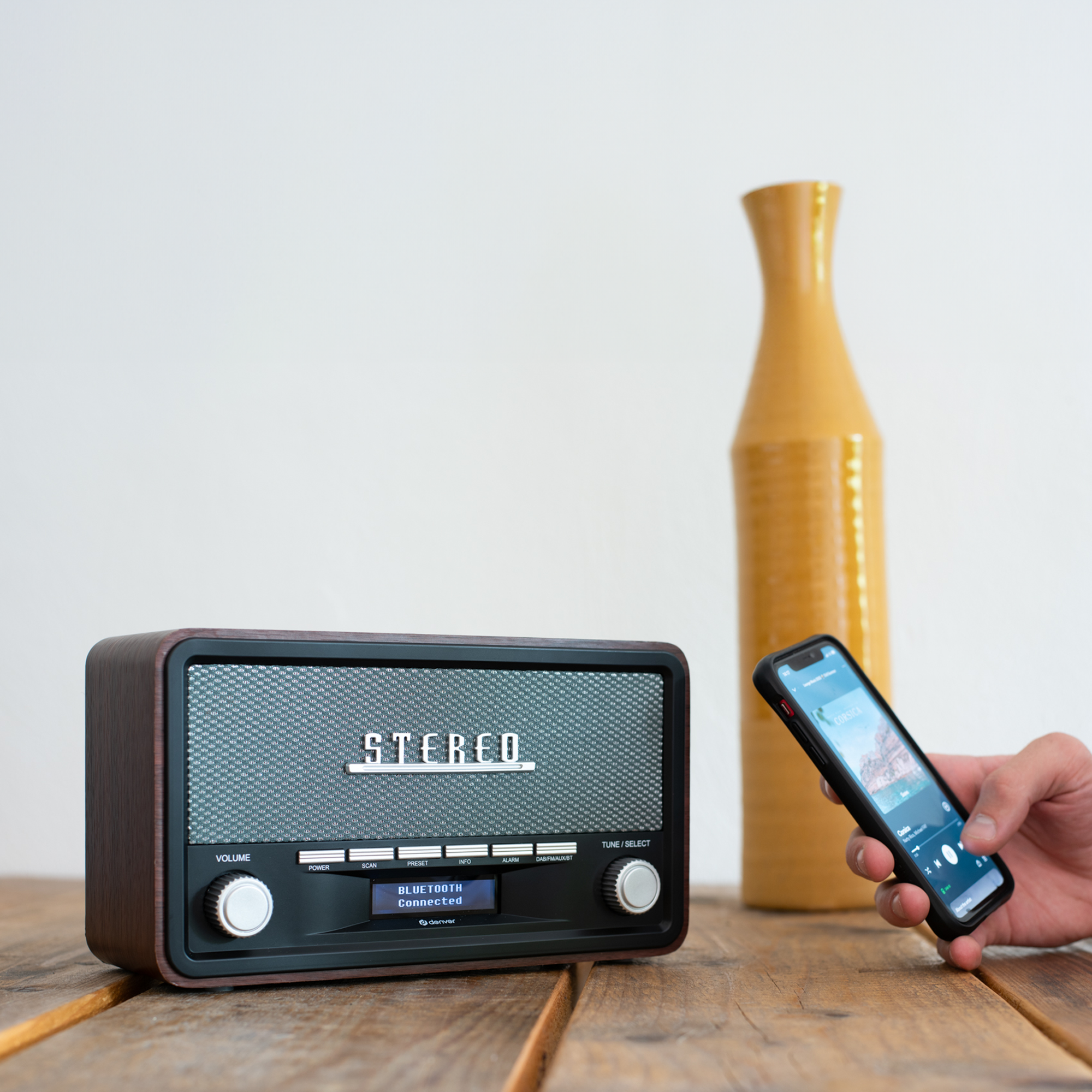 Radio w stylu vintage i telefon wyświetlający aplikację muzyczną. Drewniana powierzchnia.