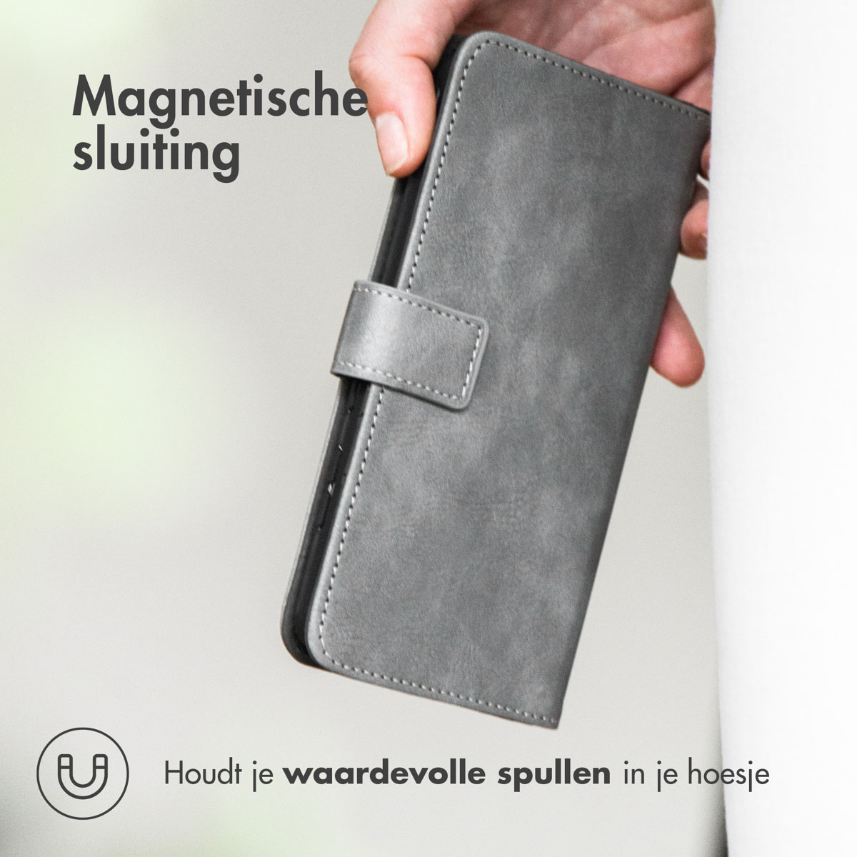 Een grijze telefoonhoes in een hand. Het heeft een magnetische sluiting en een textuur.