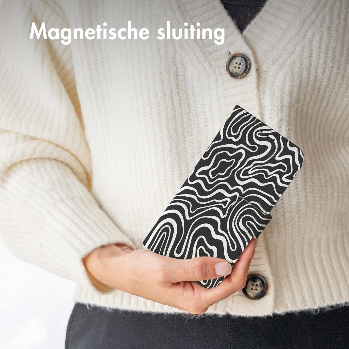Een persoon die een telefoonhoes vasthoudt met een zwart-wit wervelontwerp.