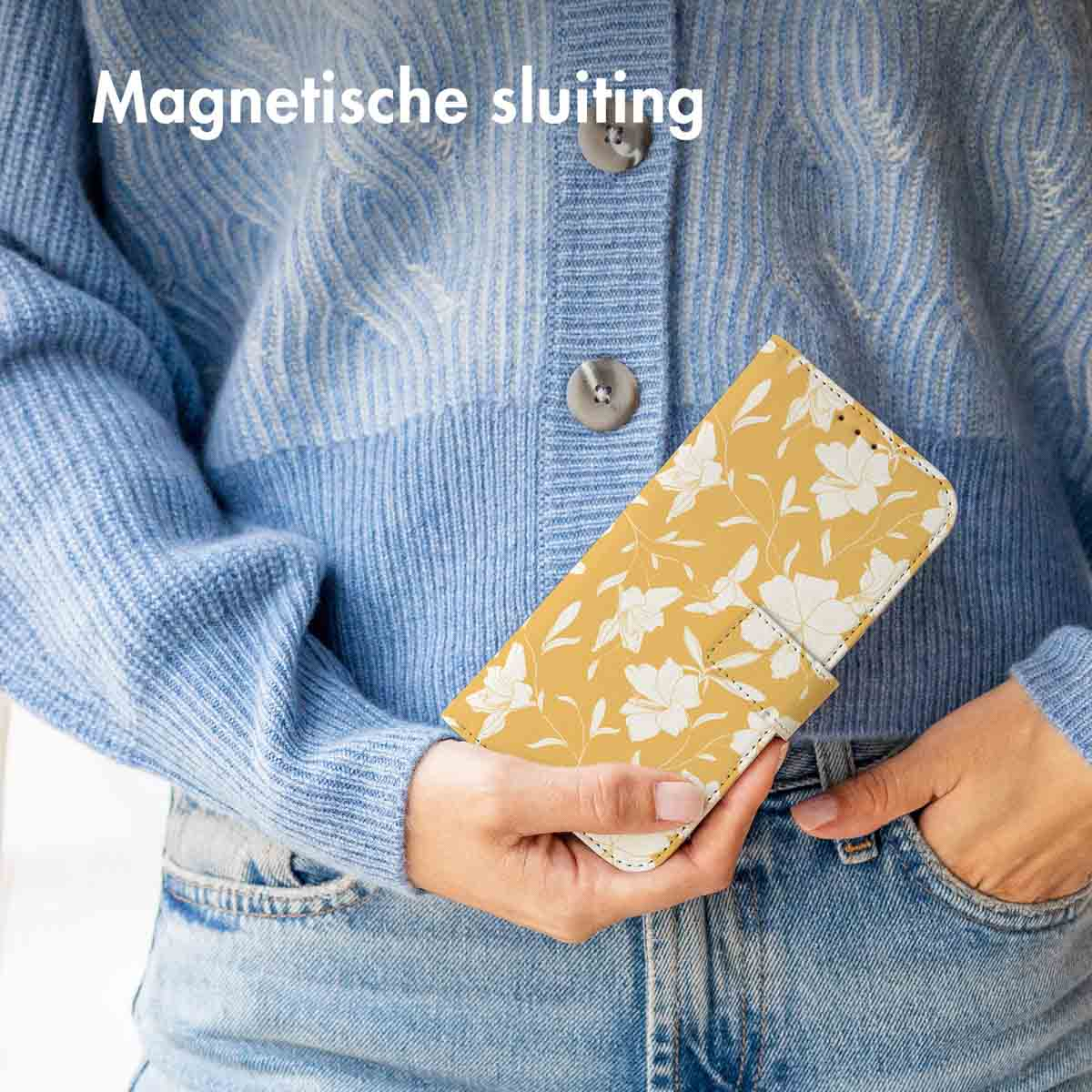 Une personne tenant un étui de téléphone jaune avec des motifs floraux blancs.