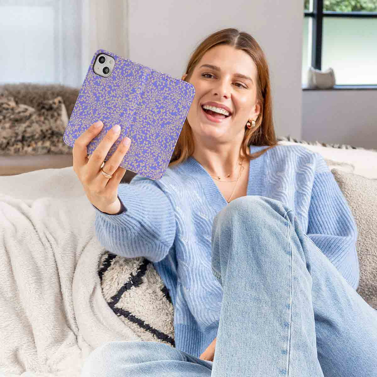Een lachende vrouw die een telefoon met een bloemige paarse hoes vasthoudt.