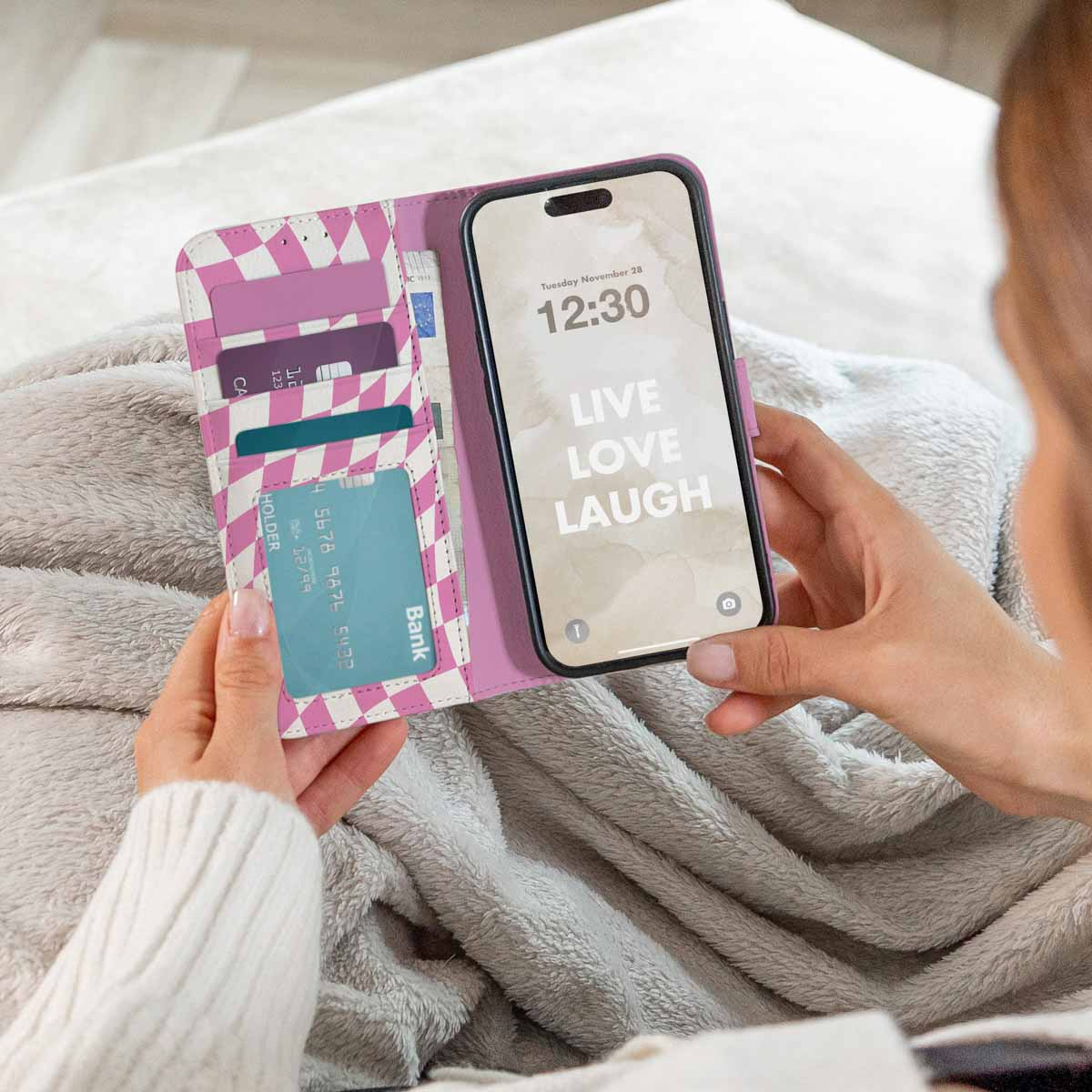 Frau hält Telefon in rosa Hülle mit sichtbaren Karten.