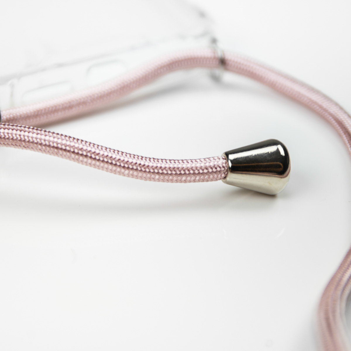 Gros plan d'un cordon de téléphone rose avec une extrémité conique métallique et fond blanc.