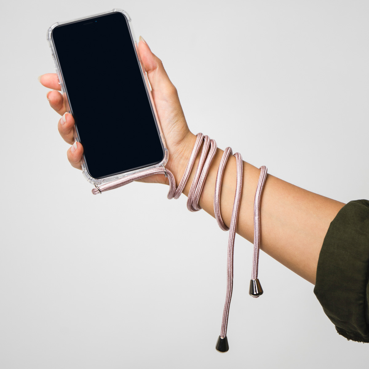 Eine Hand hält ein Smartphone in einer transparenten Hülle mit einem pinkfarbenen Kabel, das um das Handgelenk gewickelt ist.