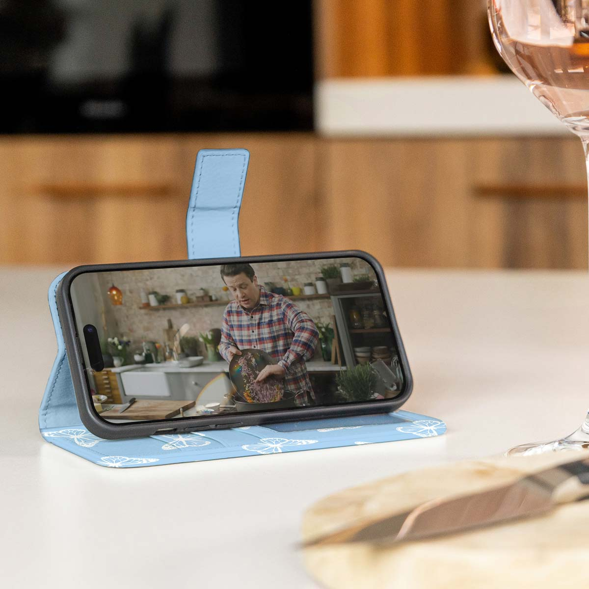 Telefoonhoesje met een telefoon waarop een man in een keuken aan het koken is.