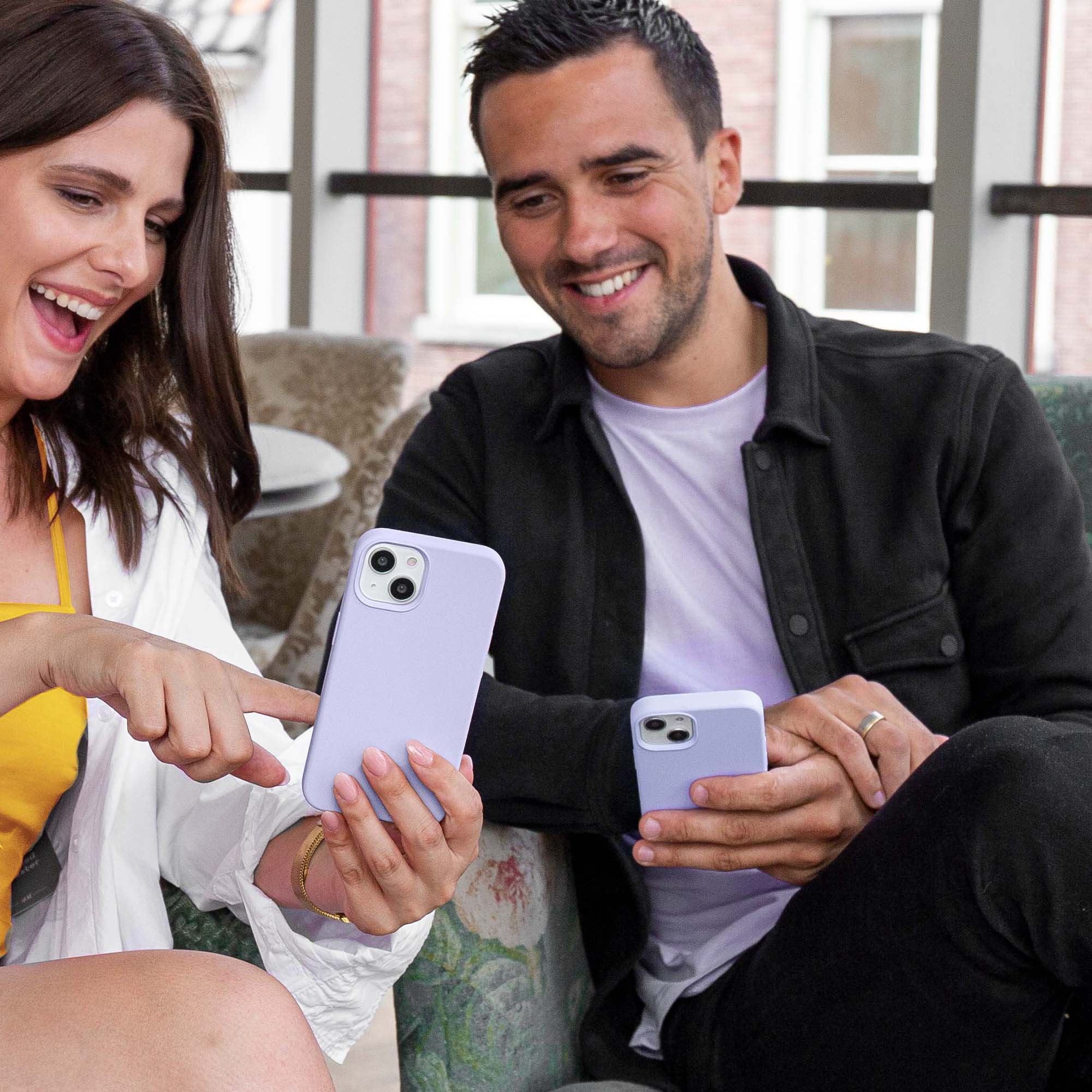 Een stel dat een lila telefoon vasthoudt. De vrouw draagt een geel overhemd en de man een zwart overhemd.