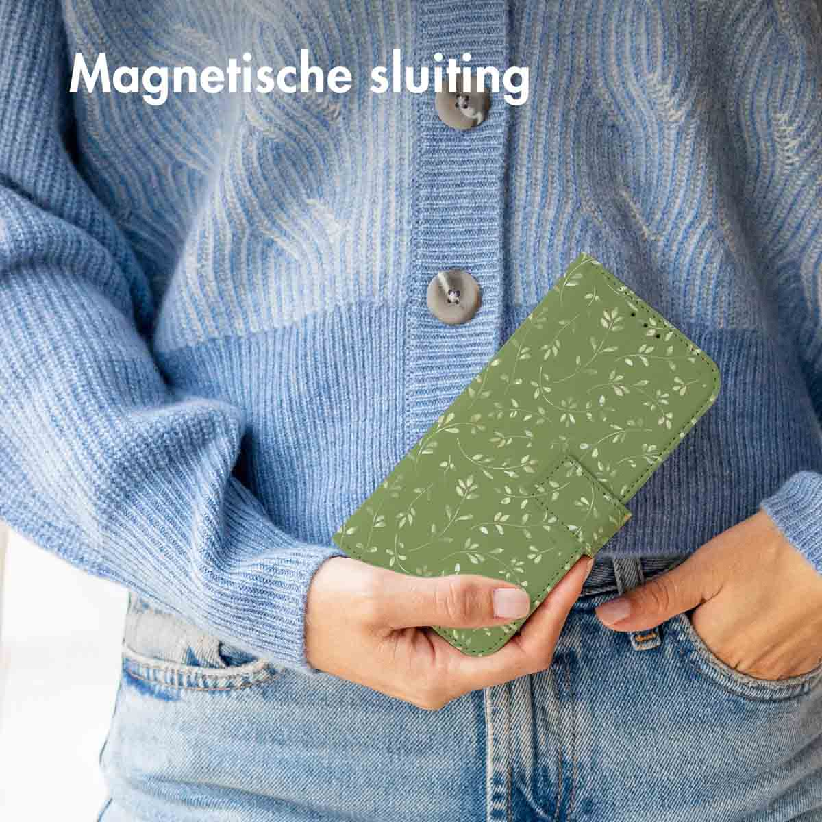 Vrouw houdt groene telefoonhoes met bloempatroon vast, blauwe jeans.