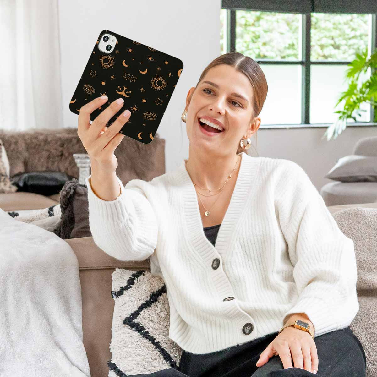 Vrouw houdt telefoonhoes vast met zon- en maanpatroon, glimlachend.