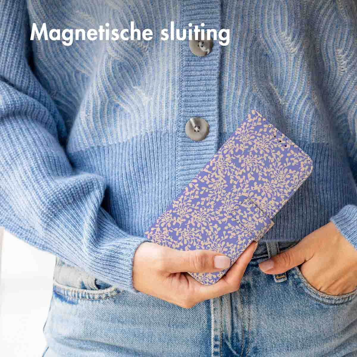 Une personne tient une coque de téléphone avec un motif floral, portant un pull bleu.