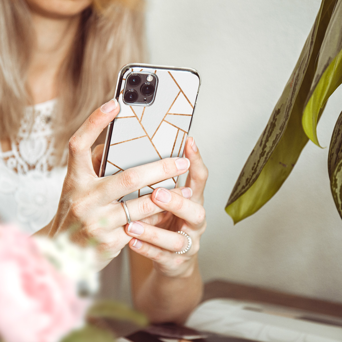 Femme tenant un téléphone avec une coque géométrique. Elle tient le téléphone avec un motif géométrique.