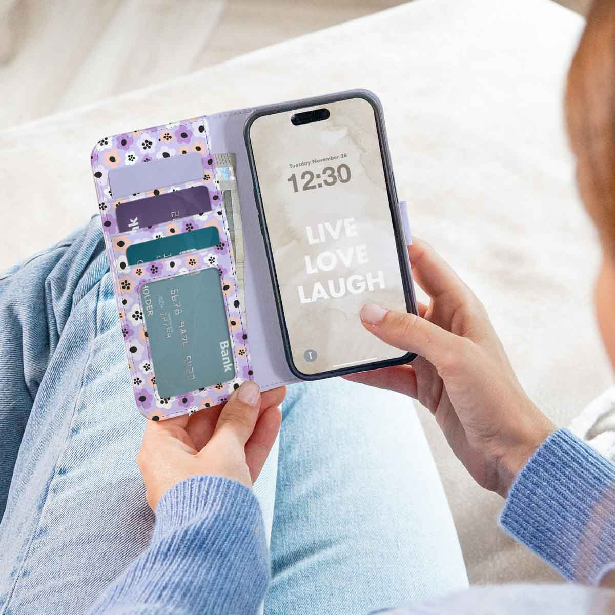 Een vrouw houdt een bloemen telefoonhoes vast en toont het telefoonscherm met 'Live Love Laugh'.