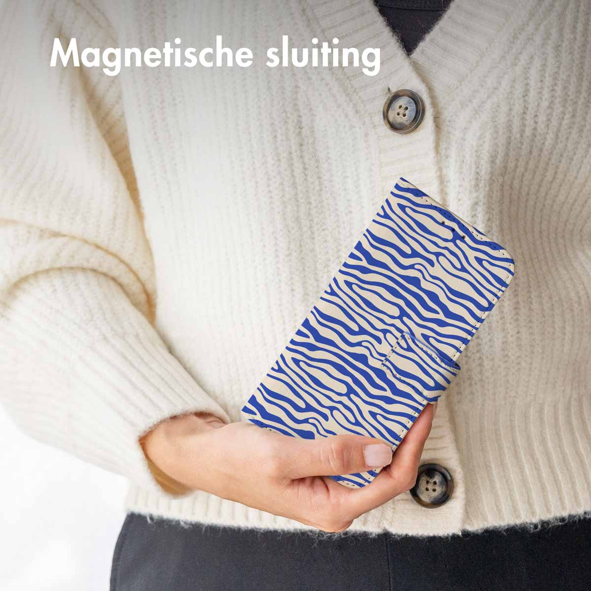 Une femme tenant une coque de téléphone bleue avec un motif bleu et blanc. La coque est fermée.
