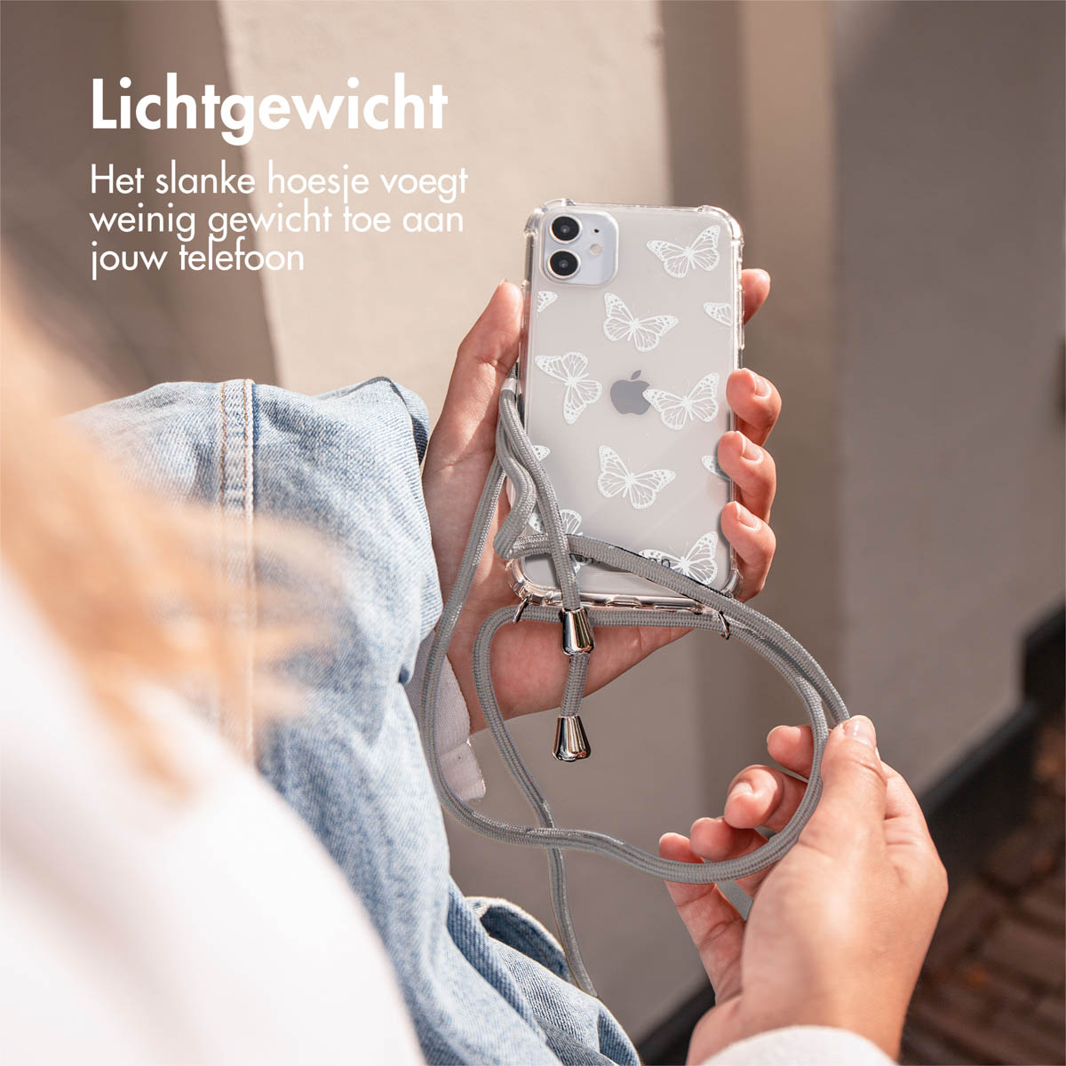 A person holding a transparent phone case with butterfly prints. The phone has a gray strap.