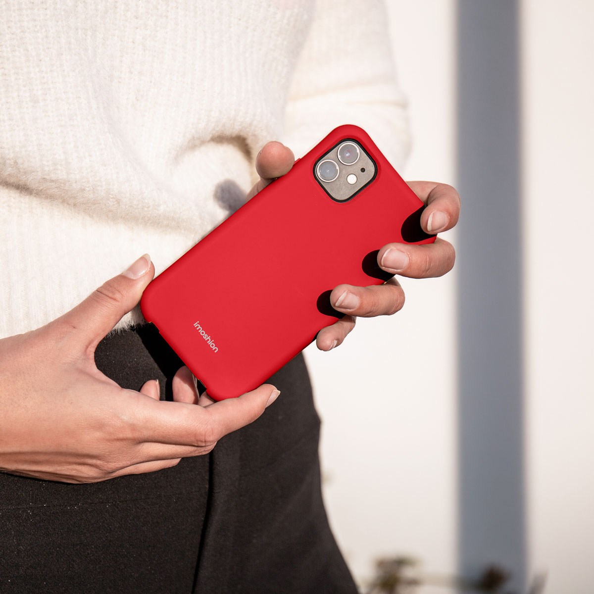 Person hält ein rotes Telefon in einer roten Hülle, mit dem imoshion-Logo auf der Hülle.