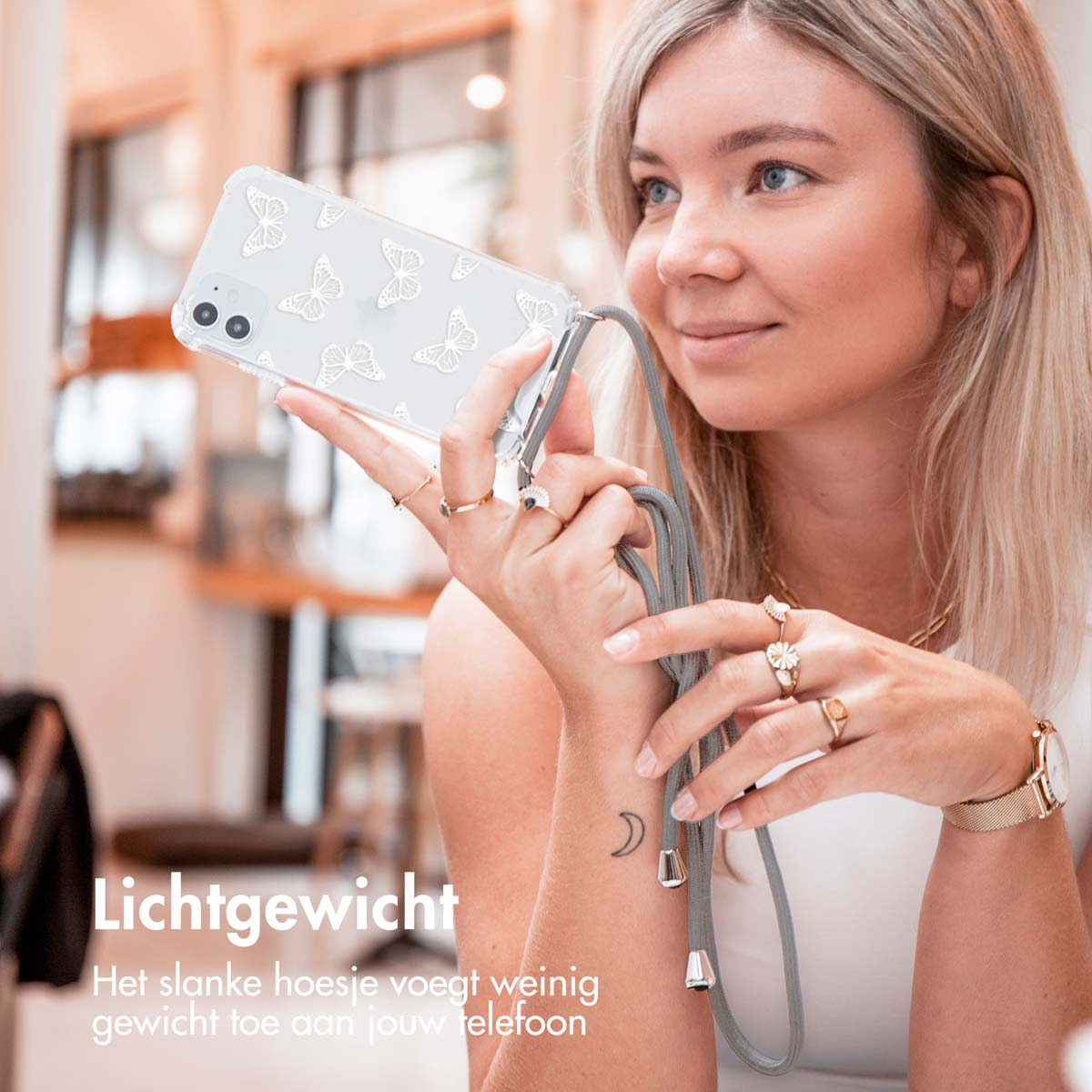 Blonde woman holding a phone in a clear case with butterflies. The phone is on a lanyard.