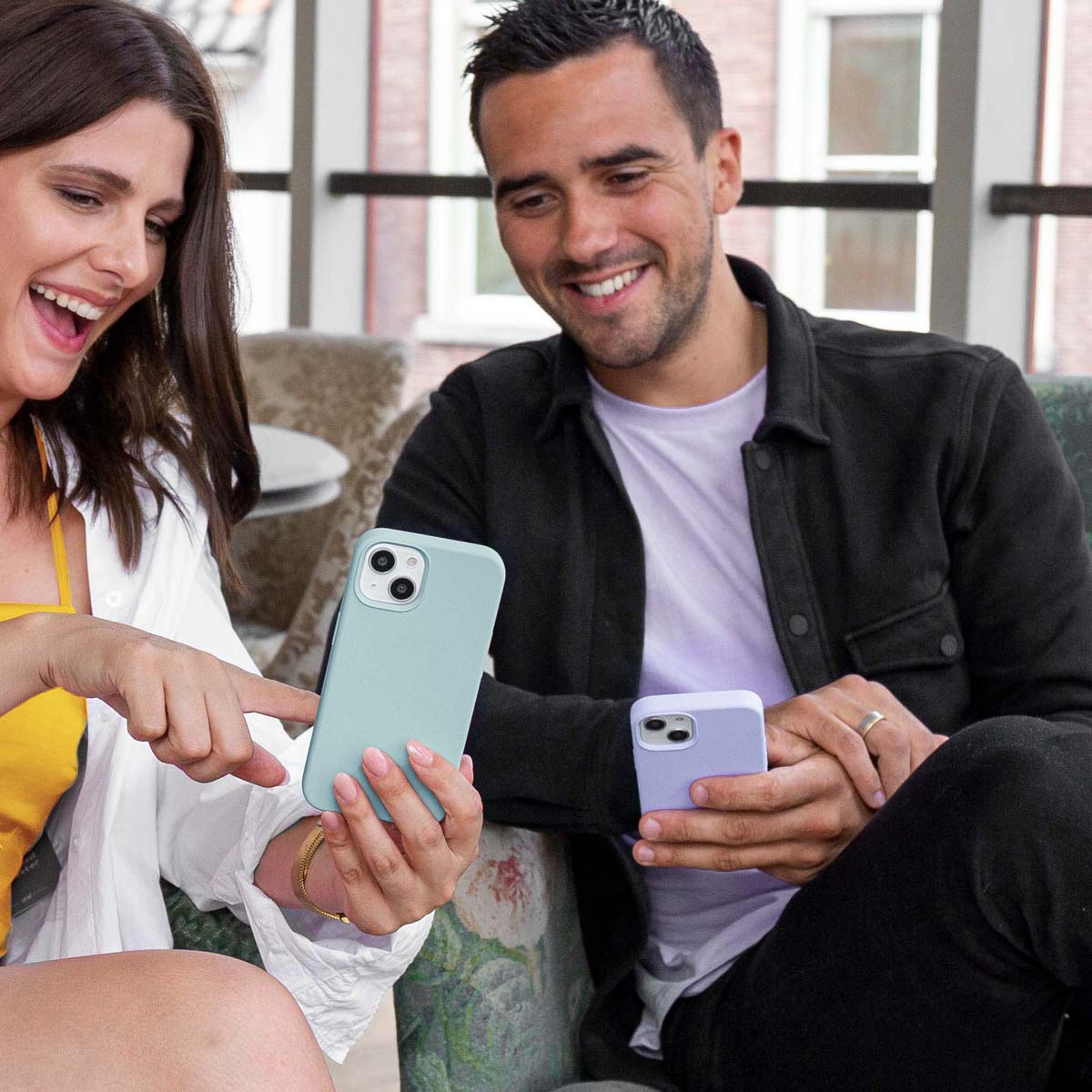 Zwei Personen halten Telefone, eines blau, eines lila, und lächeln sich an.