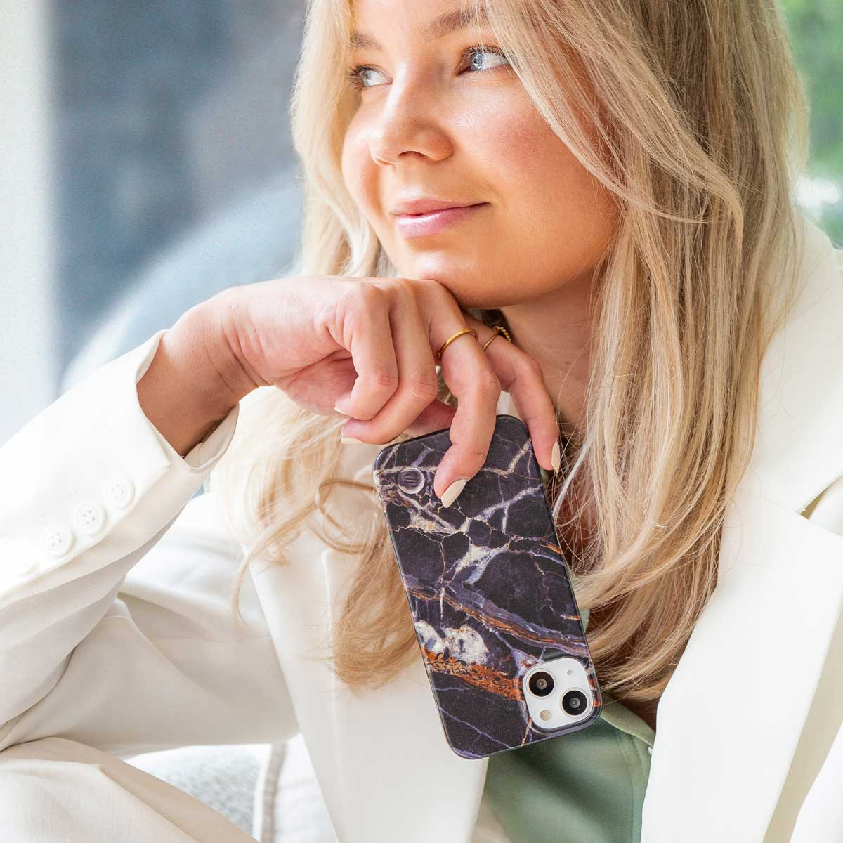 Una donna bionda tiene uno smartphone con motivo marmorizzato.