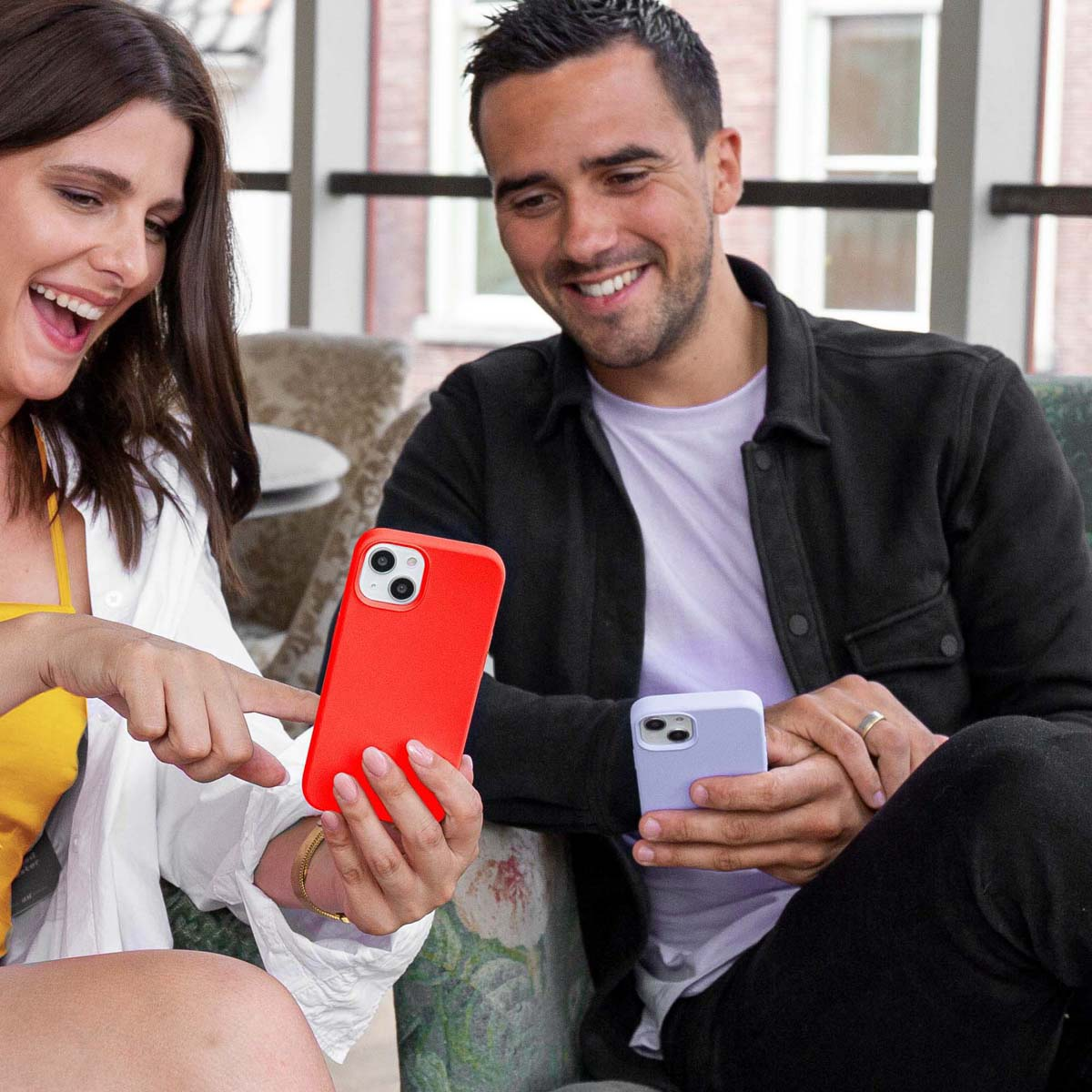 Een vrouw en een man die telefoons vasthouden. Eén is rood, de andere paars.