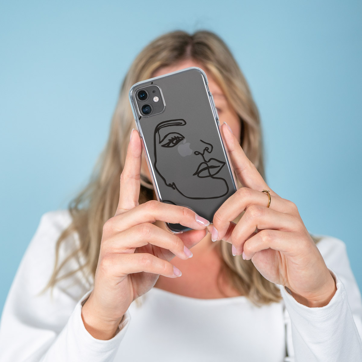 Telefono in una custodia trasparente tenuto da una donna. Lo sfondo è blu.