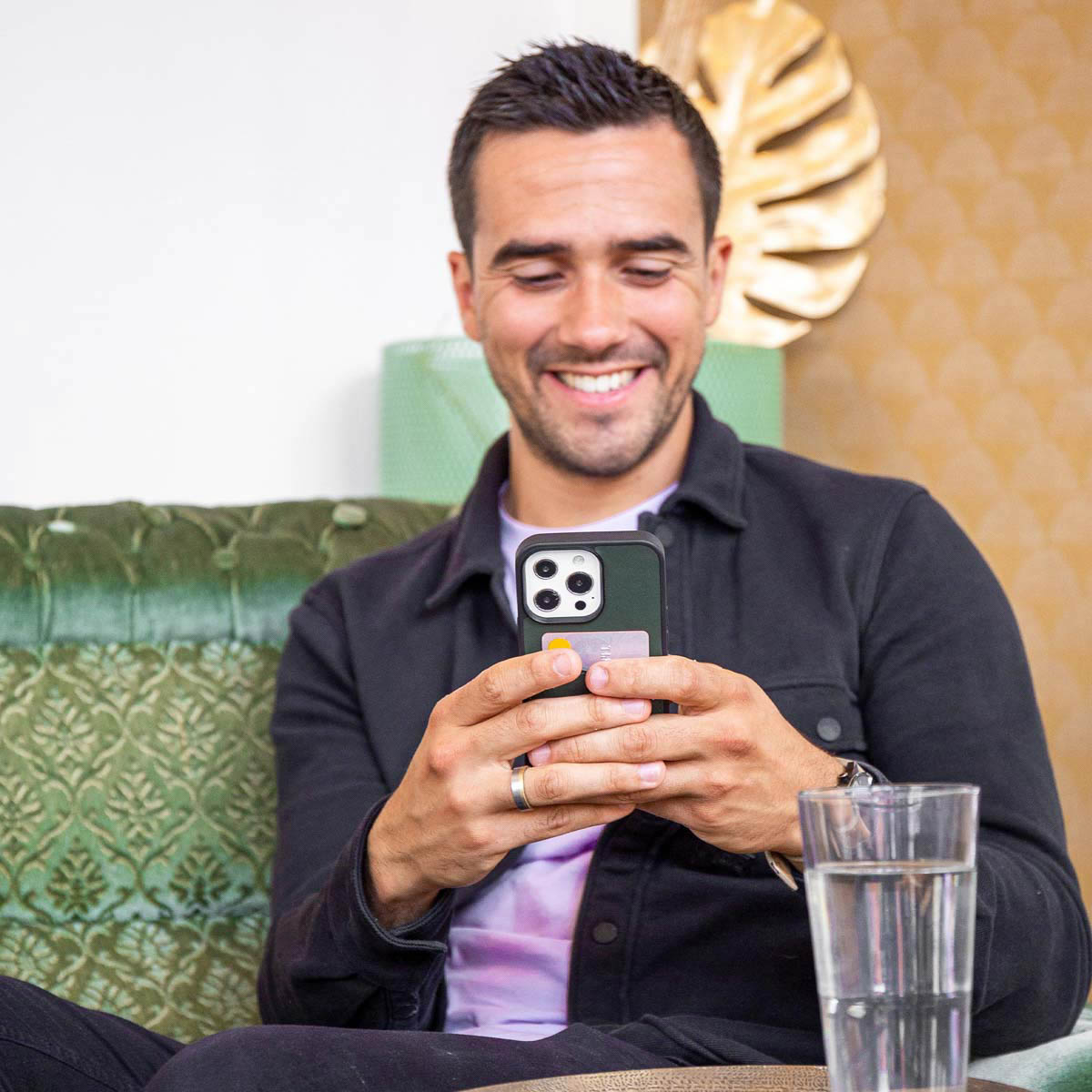 Homme souriant tenant un téléphone avec une coque et une carte.