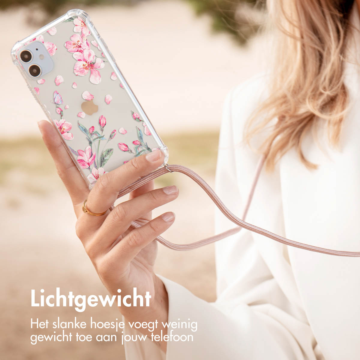 De hand van een vrouw houdt een telefoon vast met een transparante hoes met roze bloemenprint.