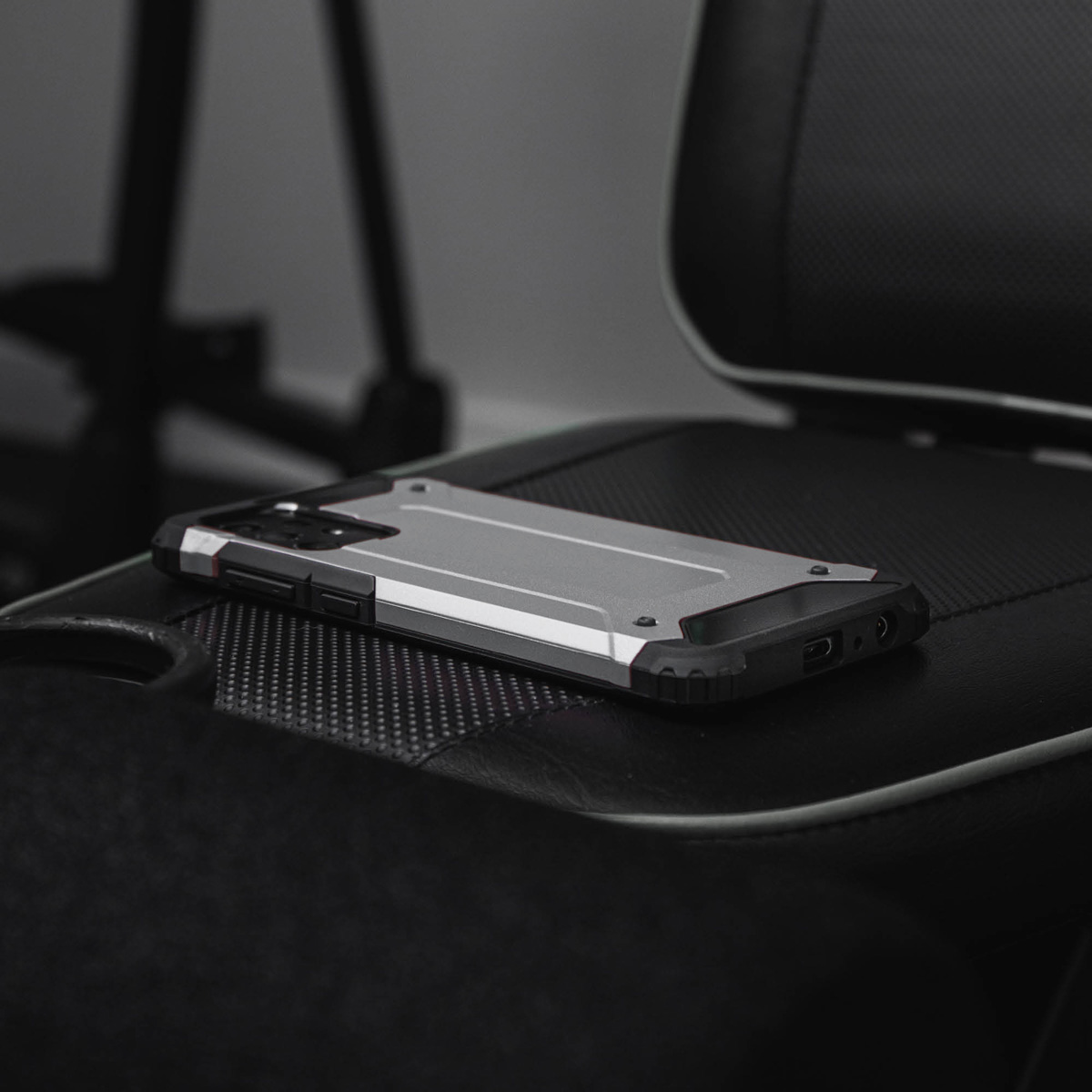 Coque de téléphone argentée et noire sur une chaise noire et grise. Arrière-plan flou.