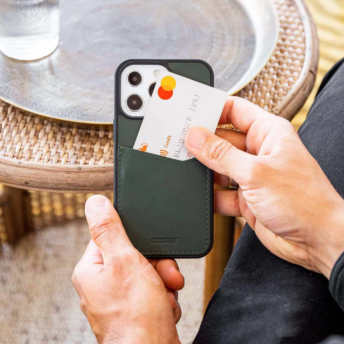 Une main tenant un téléphone avec une carte dans l'étui. L'étui est vert.