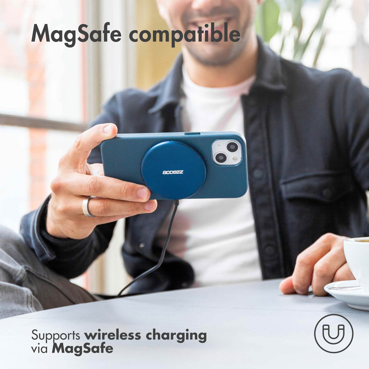 Man die een telefoon vasthoudt met een blauwe MagSafe. De telefoon laadt draadloos op.
