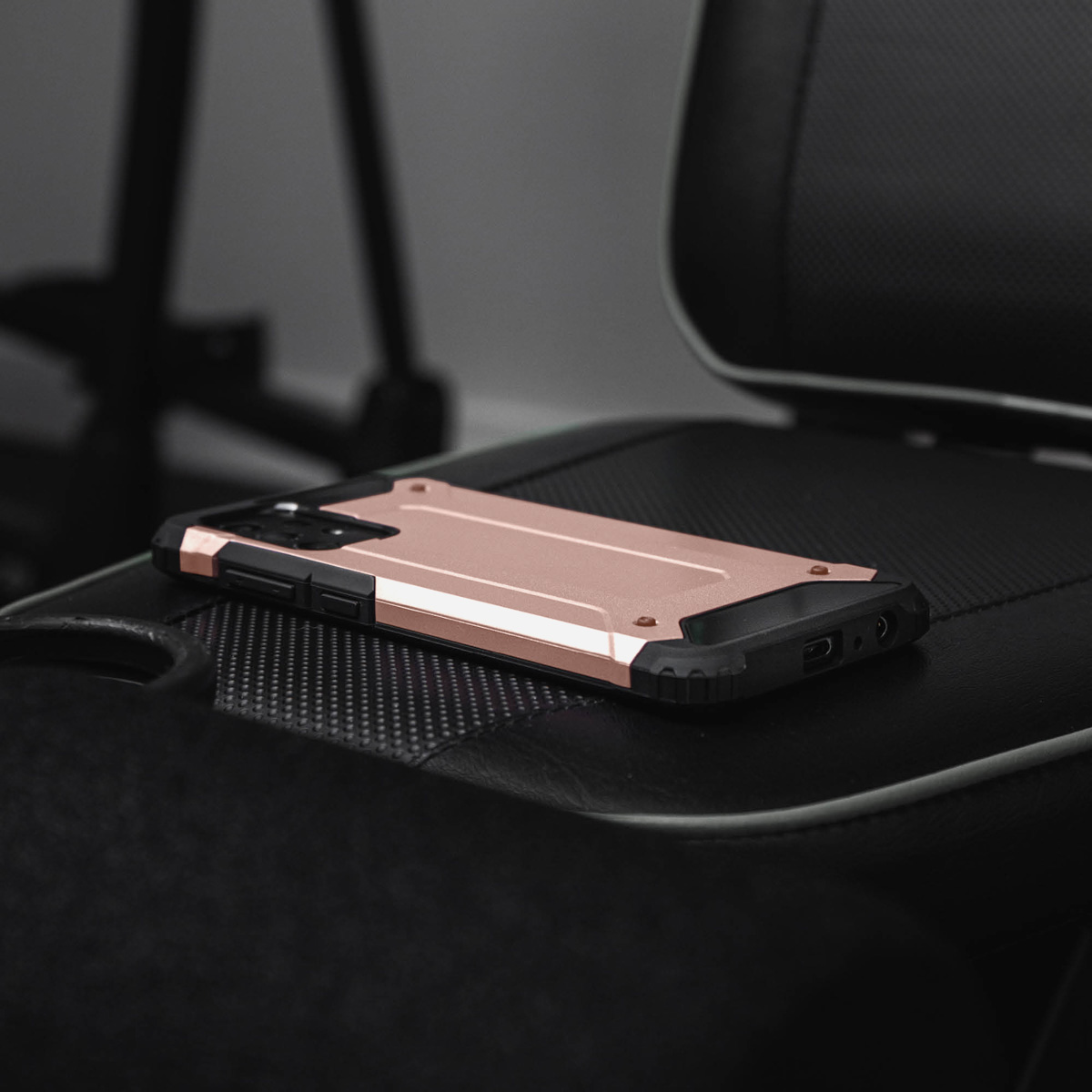 Une coque de téléphone or rose repose sur une chaise noire.