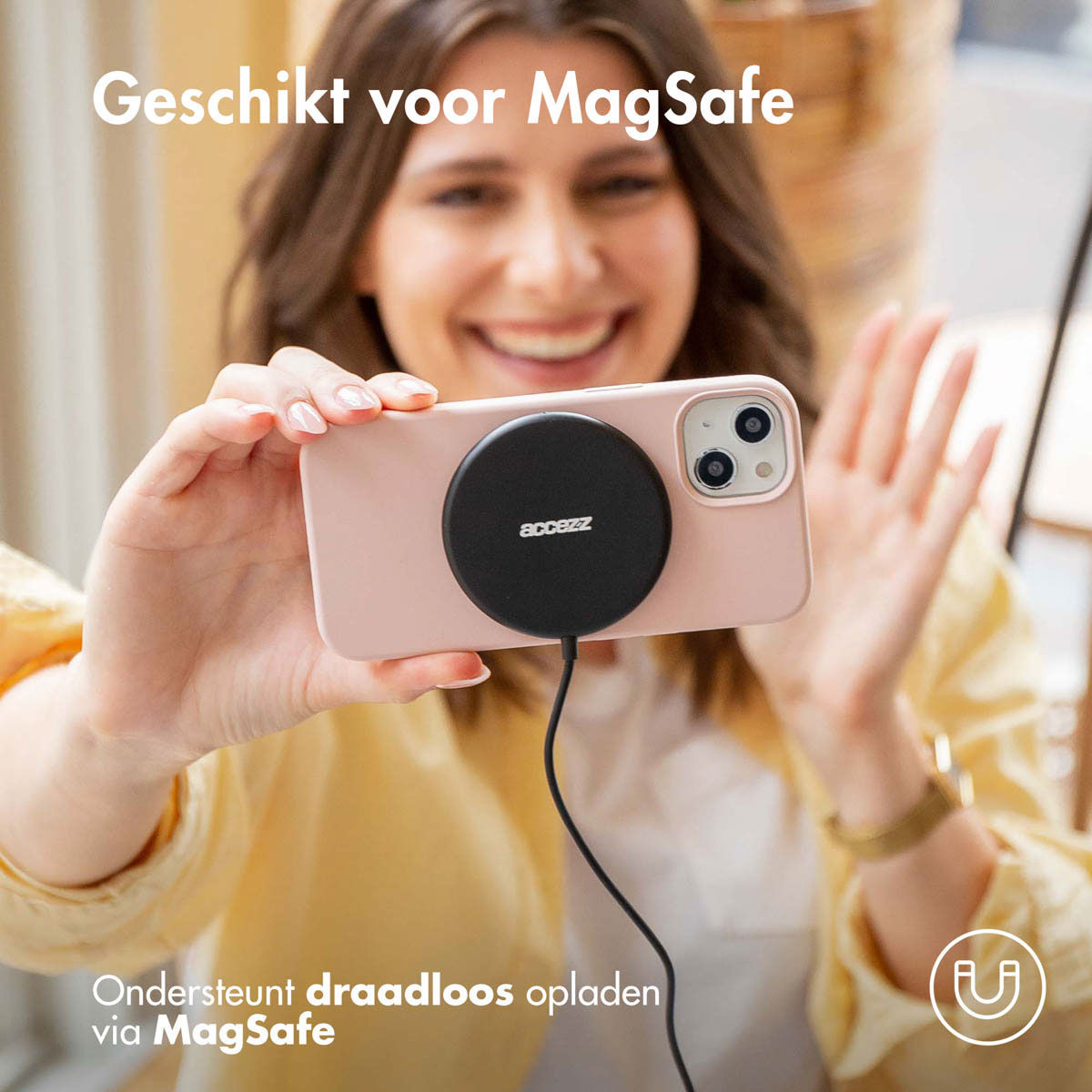 Een vrouw houdt een telefoon vast met een MagSafe-lader. Tekst: Geschikt voor MagSafe. Ondersteunt draadloos opladen via MagSafe.
