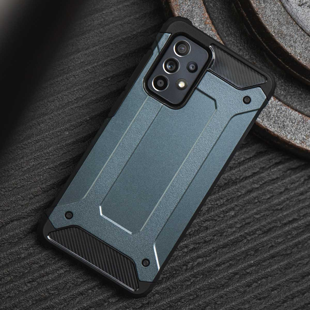 Coque de téléphone bleu-gris sur une surface sombre, avec un design texturé et des trous pour la caméra.