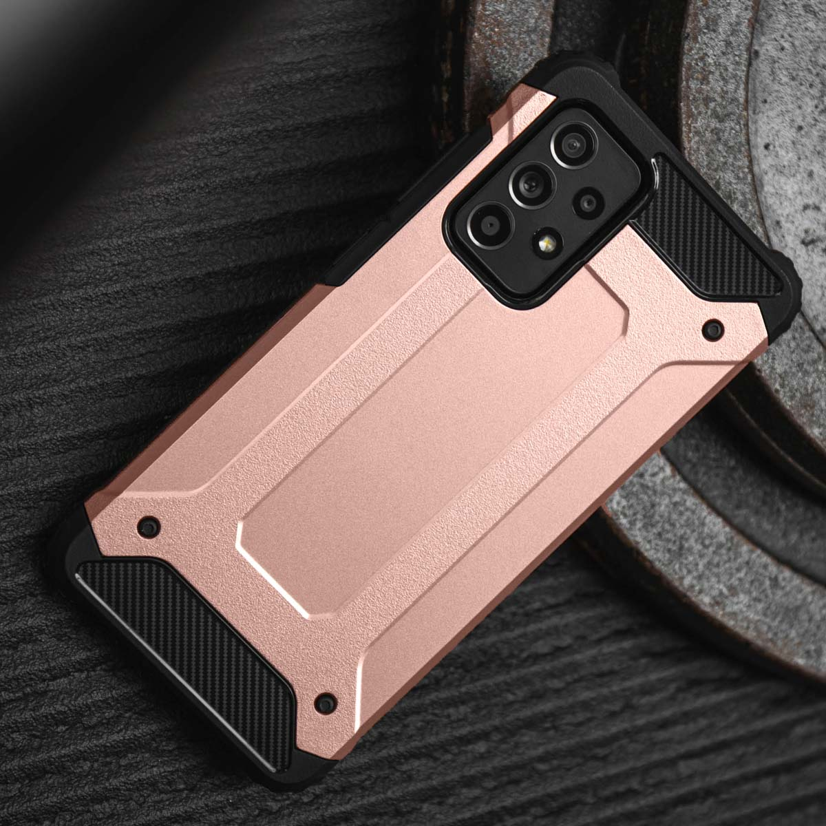 Une coque de téléphone or rose avec insert noir et module caméra repose sur une surface sombre.