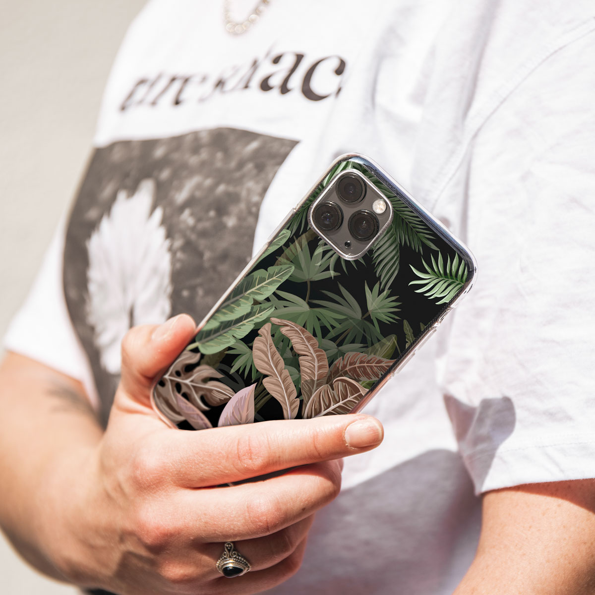 Persoon die telefoon vasthoudt met een zwarte achtergrond en palmbladontwerp.