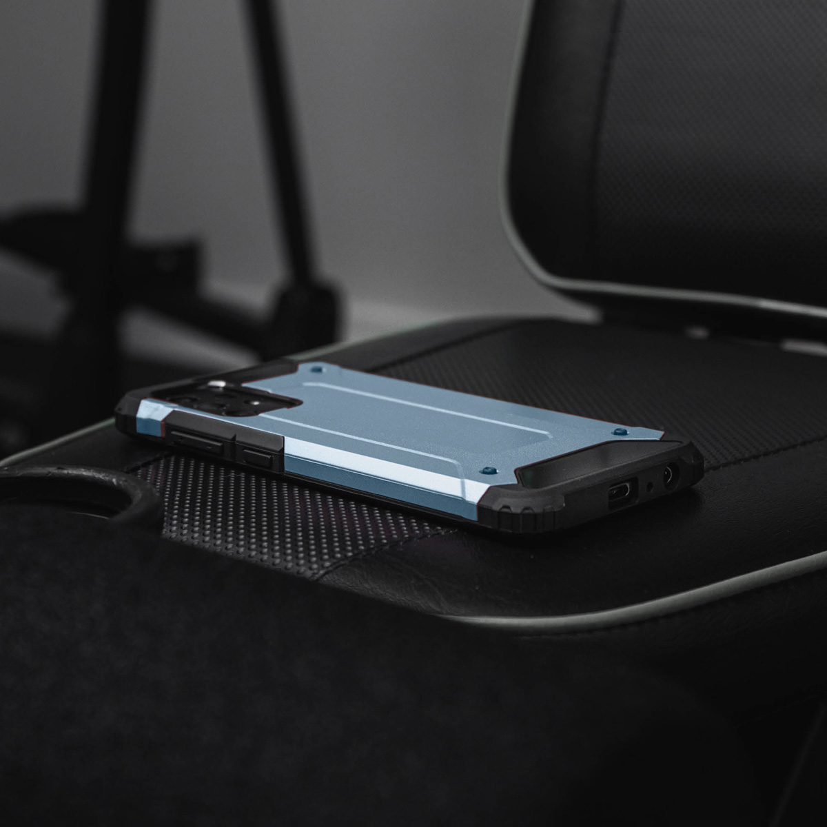 Une coque de téléphone bleue sur une chaise de bureau noire. L'arrière-plan est sombre et flou.