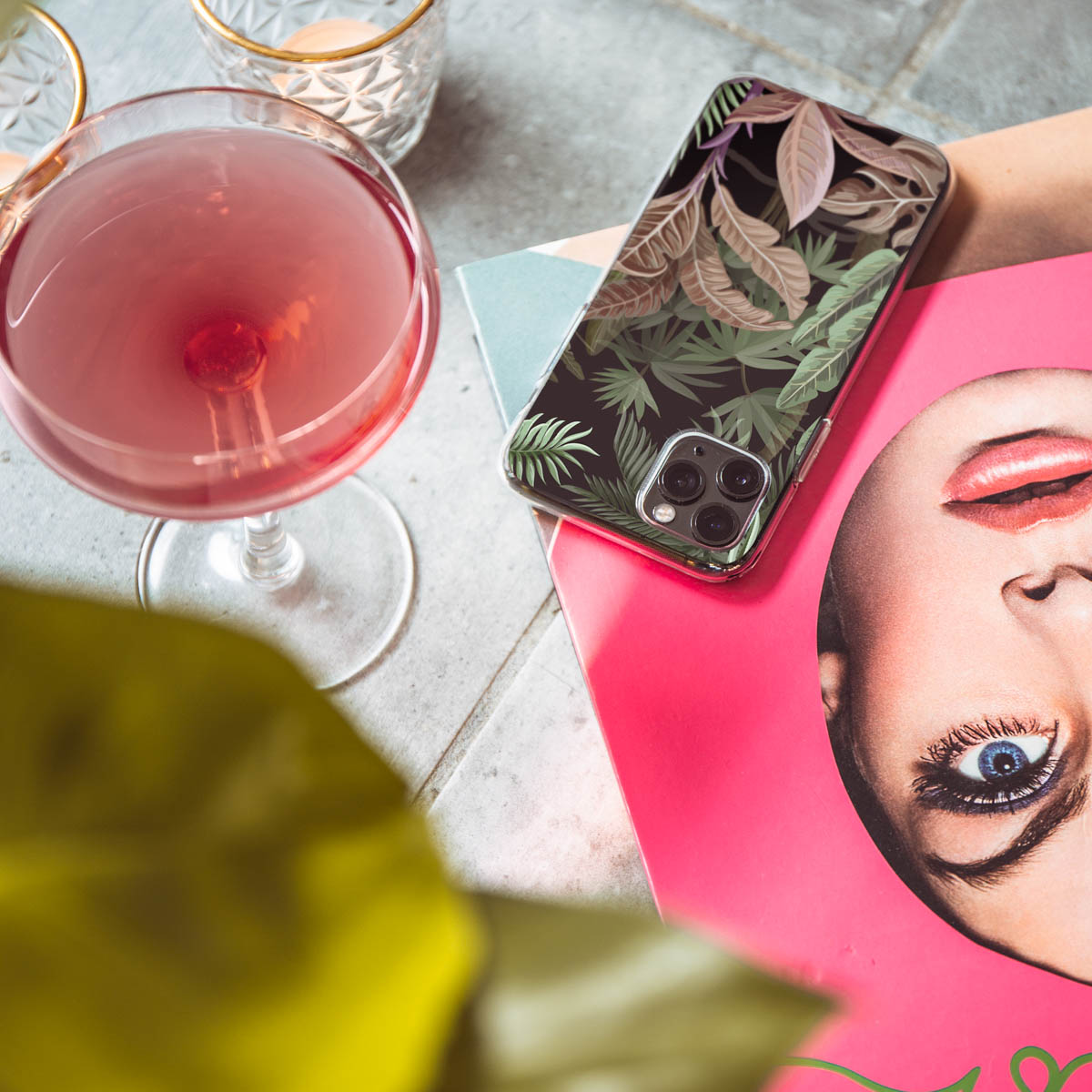 Telefoon met palmbladontwerp, een cocktail en een tijdschrift met een vrouwengezicht.