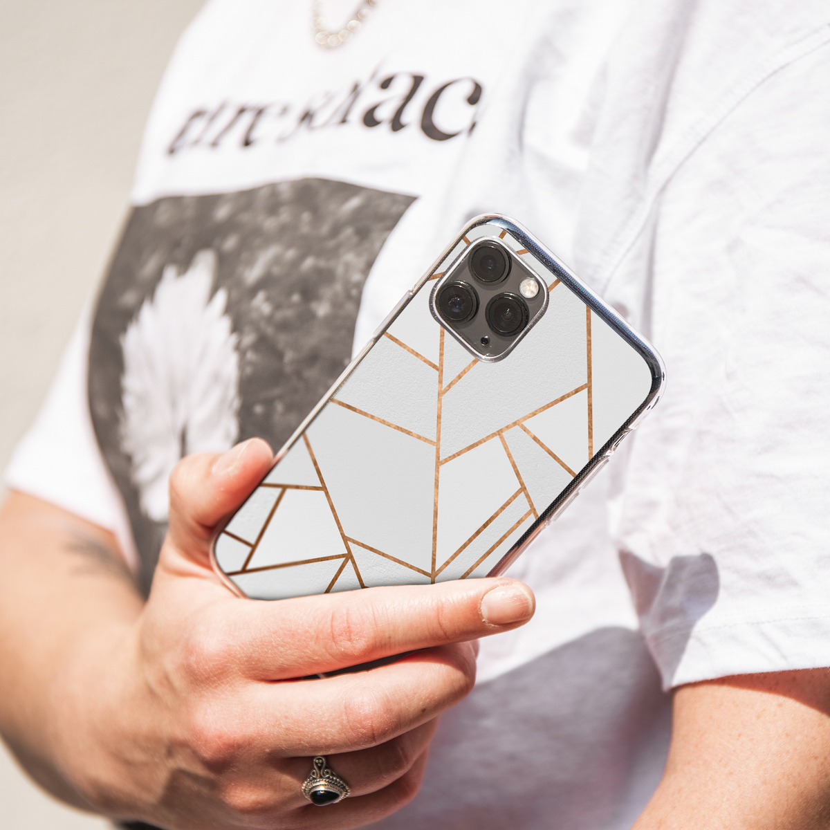 Een persoon die een telefoon vasthoudt met een geometrisch patroon hoesje, witte achtergrond.