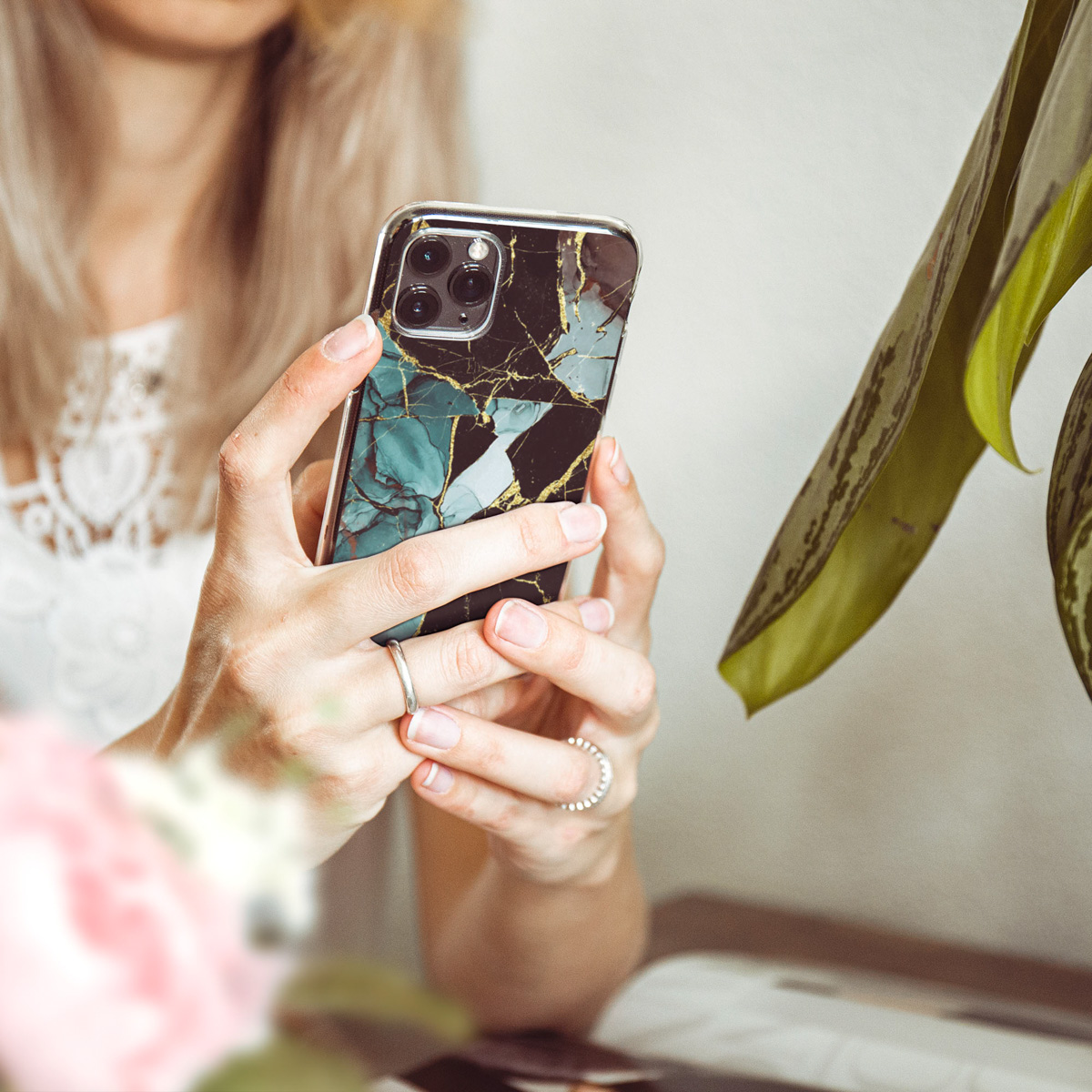 Femme tenant un téléphone avec étui en marbre. Gros plan sur les mains et le téléphone.