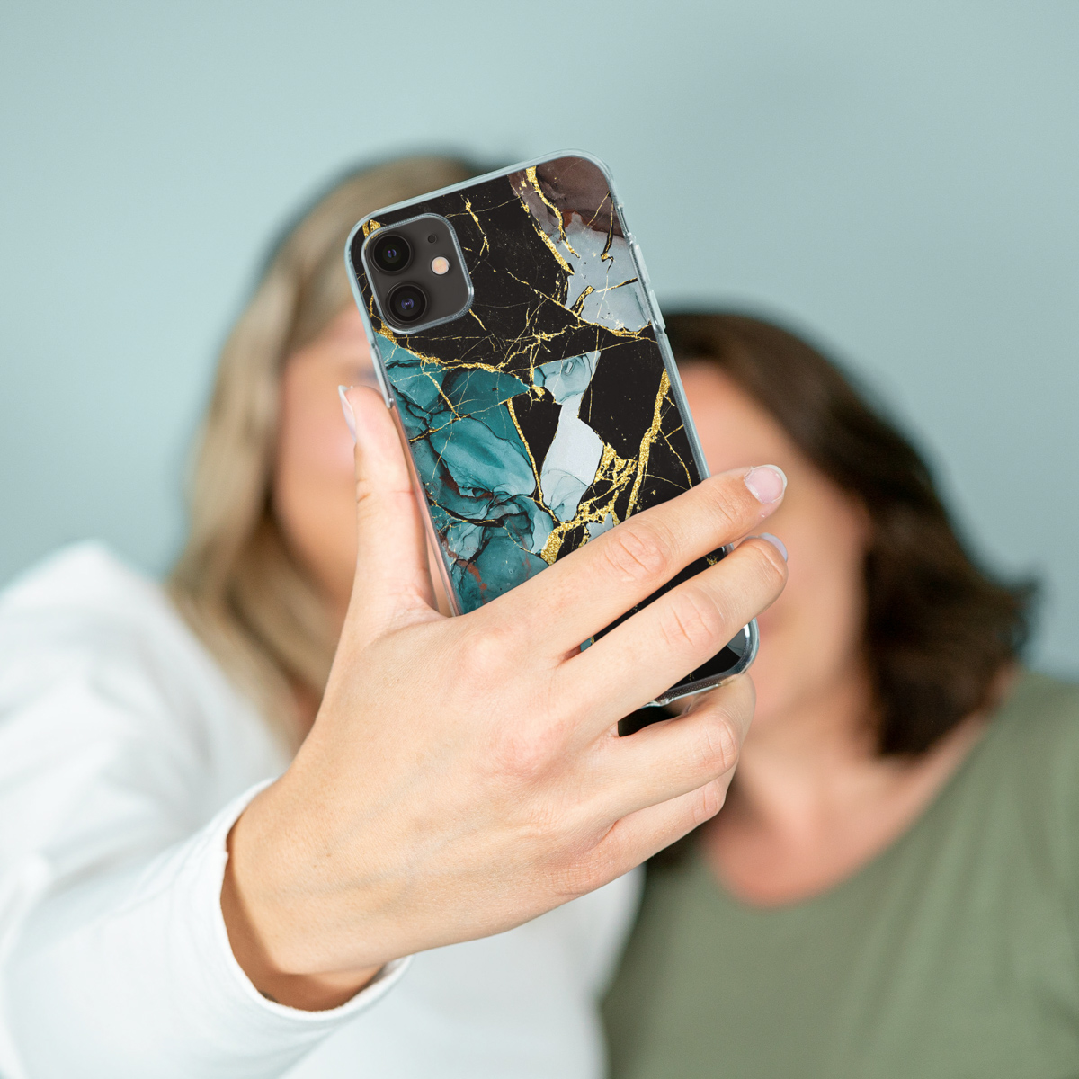 Une personne prenant un selfie avec un téléphone dans un étui en marbre.