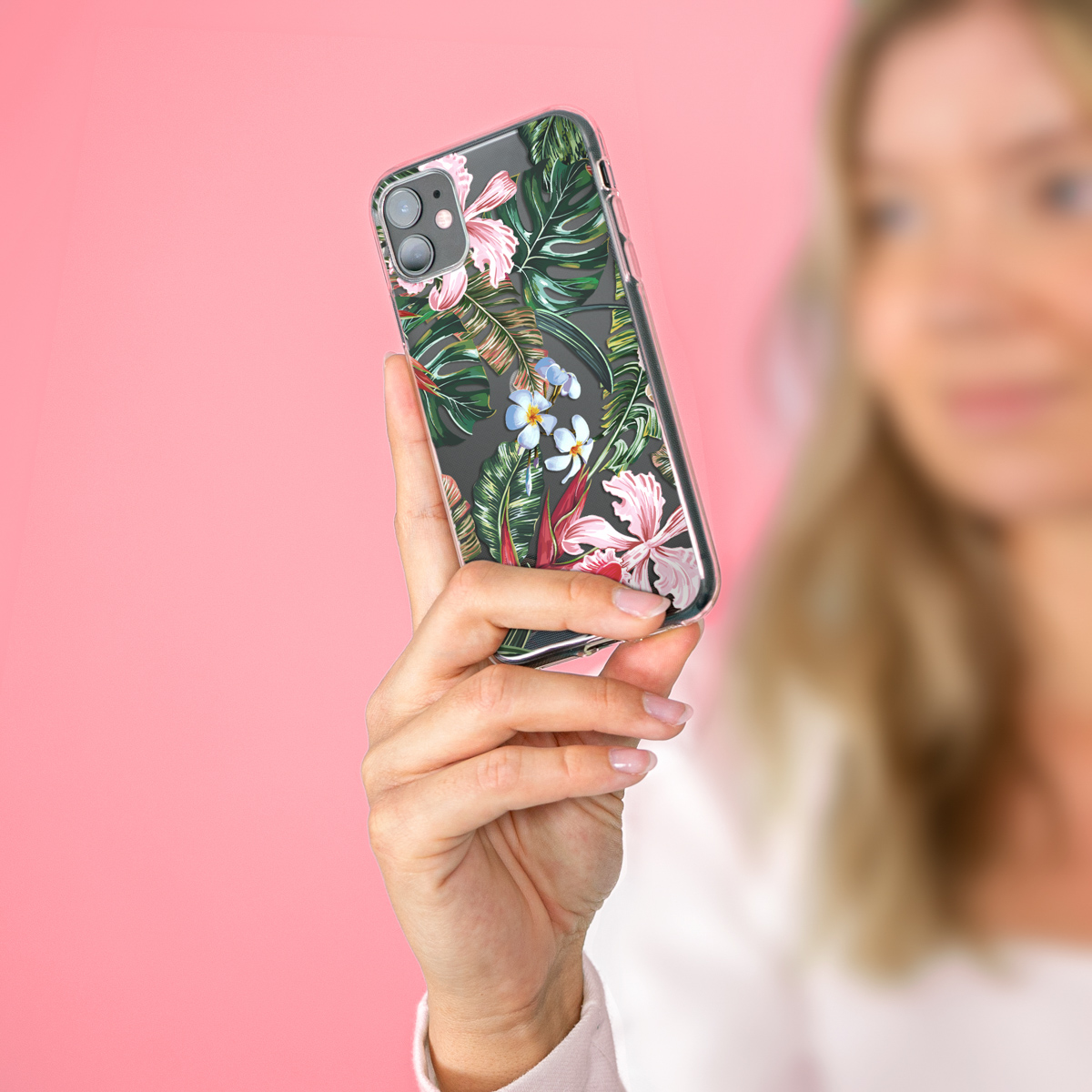 Vrouw houdt een telefoon vast in een transparante hoes met een bloemenontwerp.